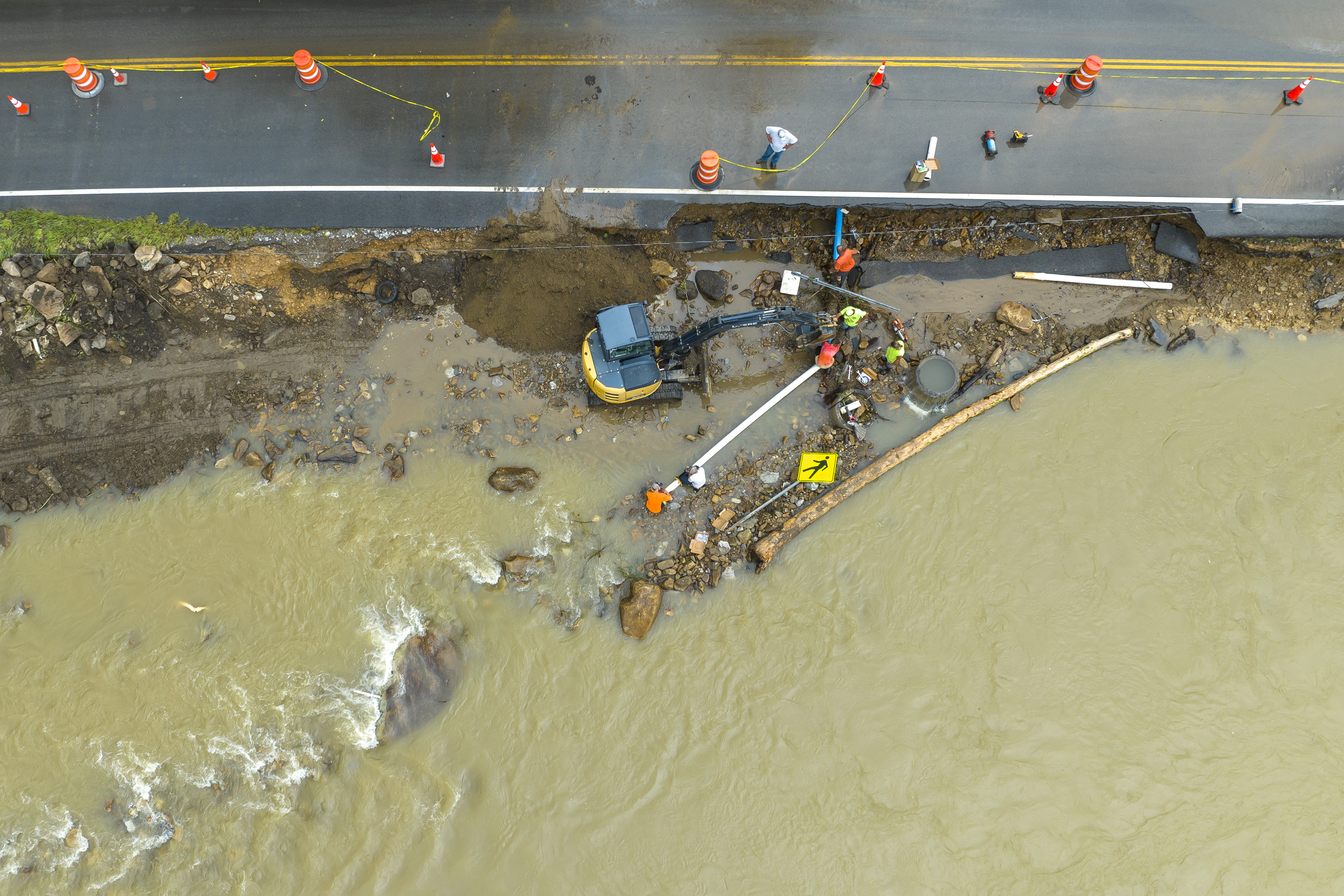 Volunteers and city workers try to reconnect the water supply to a nursing home in Elkhorn City, Ky., on Friday, July 29, 2022. The pipe, along with some of KY-197, washed away yesterday when the Russell Fork flooded. (Ryan C. Hermens/Lexington Herald-Leader via AP)