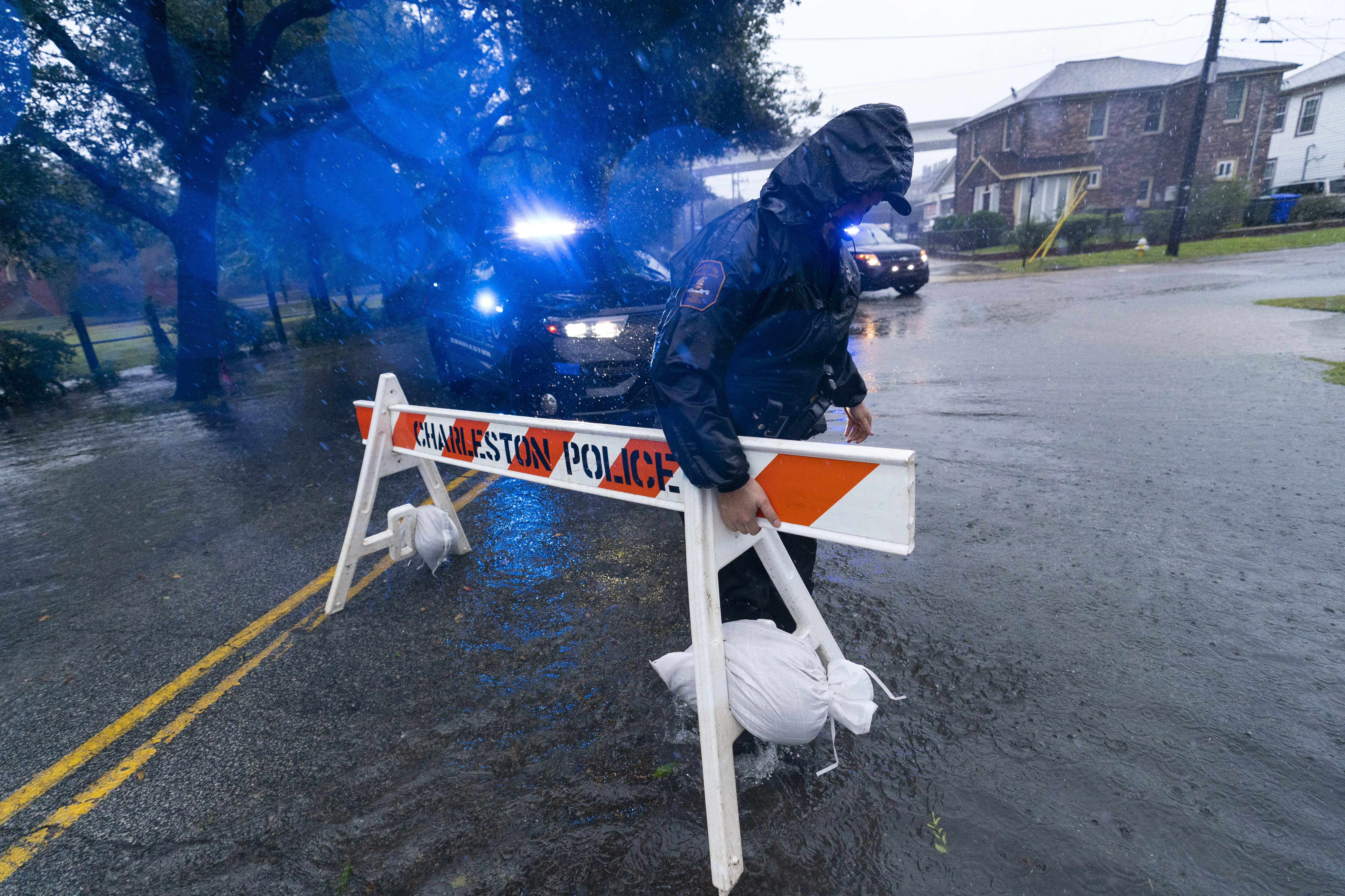 Un oficial de policía de Charleston mueve una barricada para bloquear una calle inundada mientras se sienten los efectos del huracán Ian, el viernes 30 de septiembre de 2022, en Charleston, Carolina del Sur. 