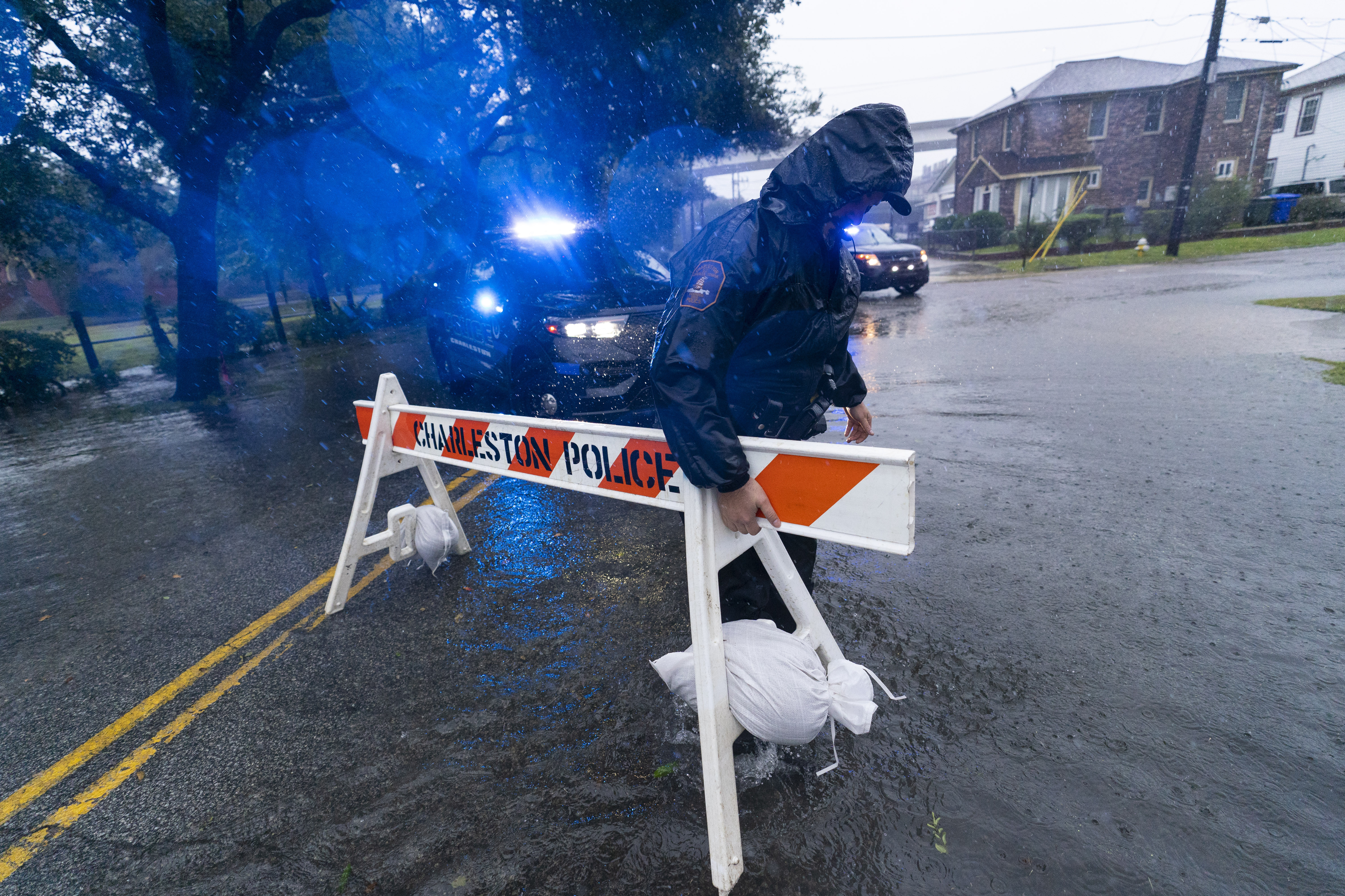 A Charleston police officer moves a barricade to block a flooded street as the effects from Hurricane Ian are felt, Friday, Sept. 30, 2022, in Charleston, S.C. 