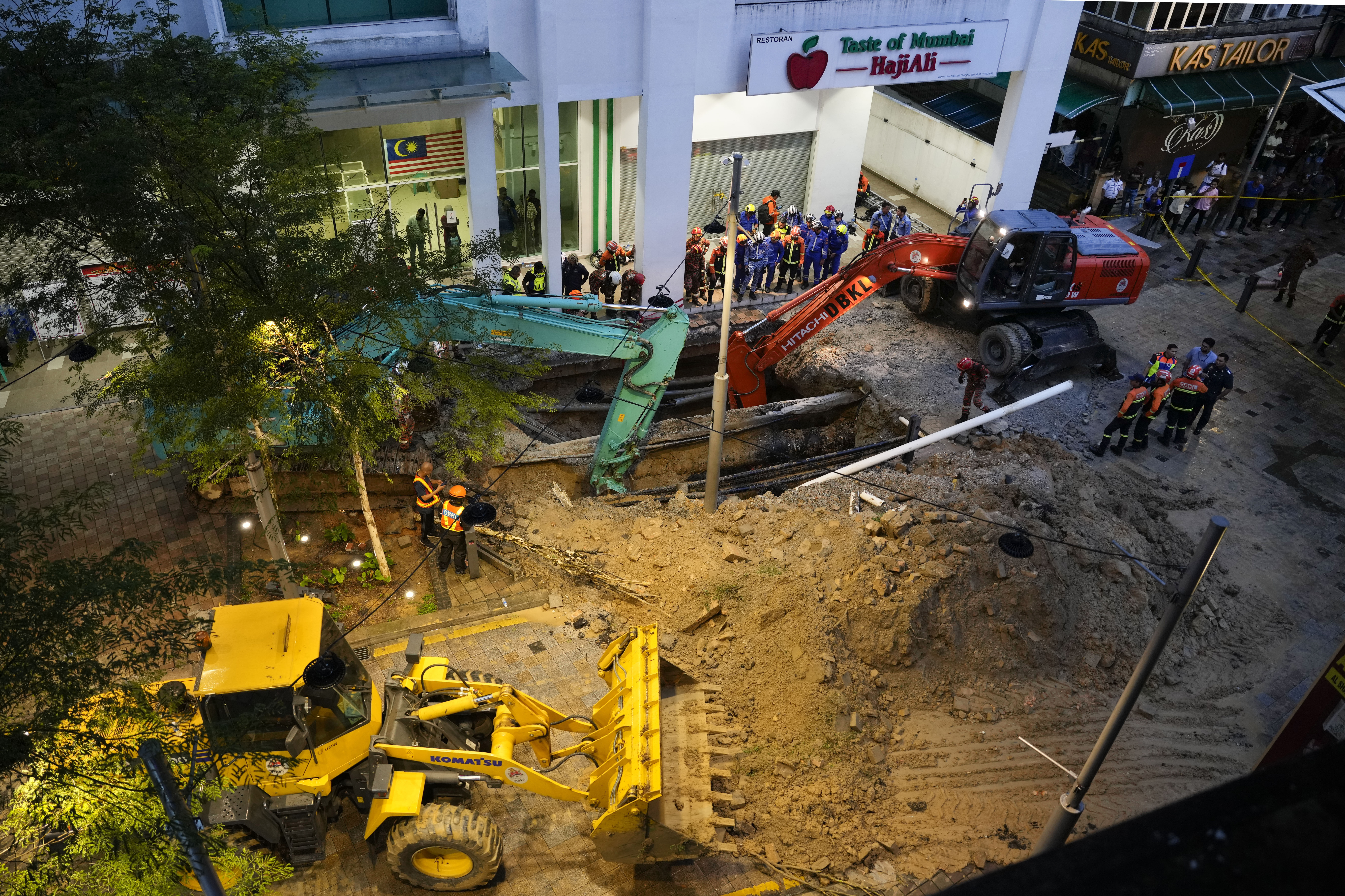 Fire and Rescue department checking on after receiving reports that a woman has fallen into the sinkhole after a section of the sidewalk caved in Kuala Lumpur, Friday, Aug. 23, 2024. 