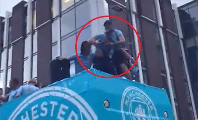 Teammates catch Jack Grealish before he falls off the Manchester City bus.