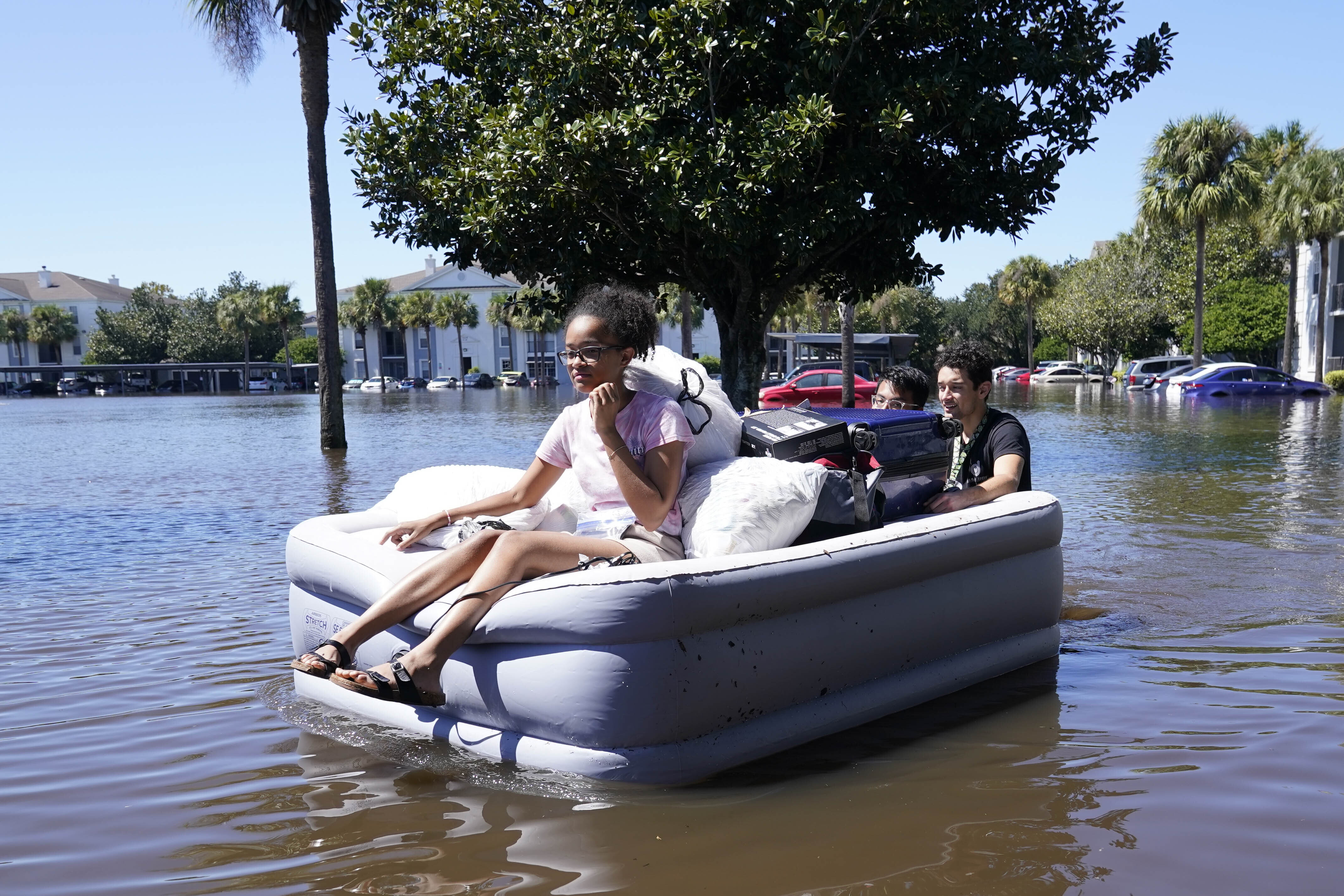University of Central Florida students use an inflatable mattress as they evacuate an apartment complex near the campus that was totally flooded by rain from Hurricane Ian, Friday, September 30, 2022, in Orlando, Florida