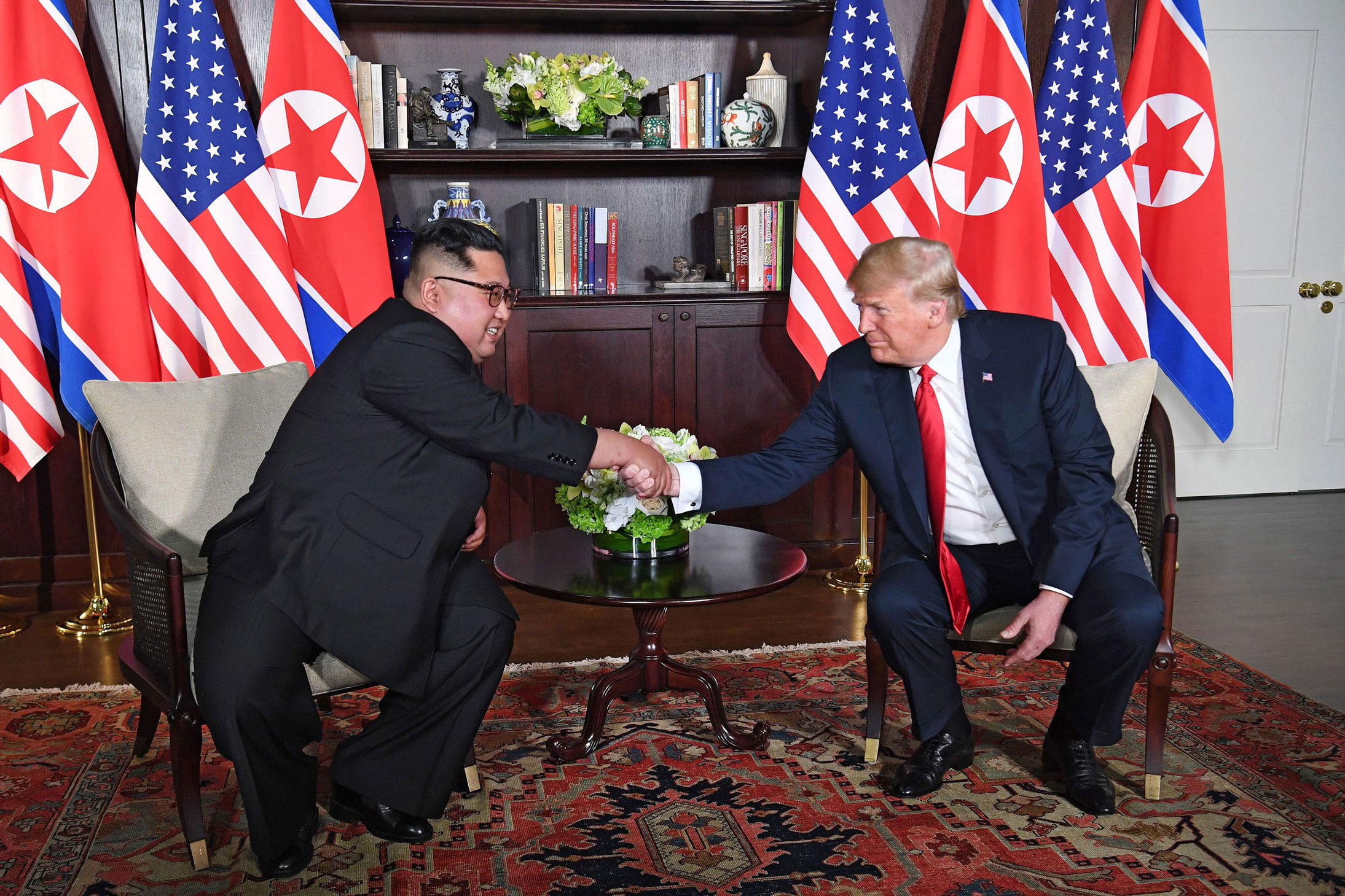 US President Donald Trump (R) shakes hands with North Korea's leader Kim Jong Un (L) as they sit down for their historic US-North Korea summit, at the Capella Hotel on Sentosa island in Singapore on June 12, 2018.
