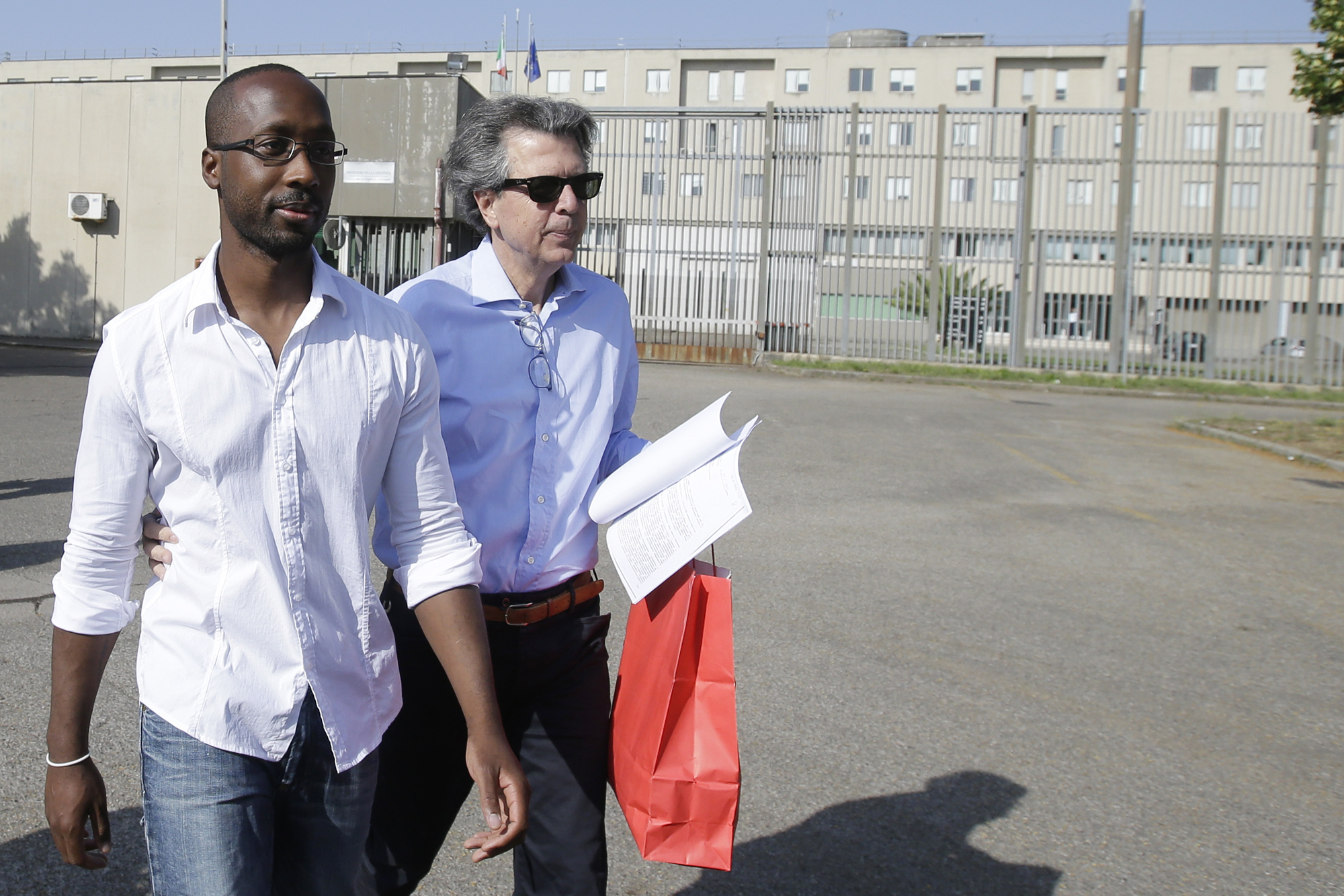 Rudy Guede, left, is greeted by an unidentified person as he leaves the penitentiary for a temporary release of thirty-six hours, in Viterbo, Italy, on June 25, 2016.