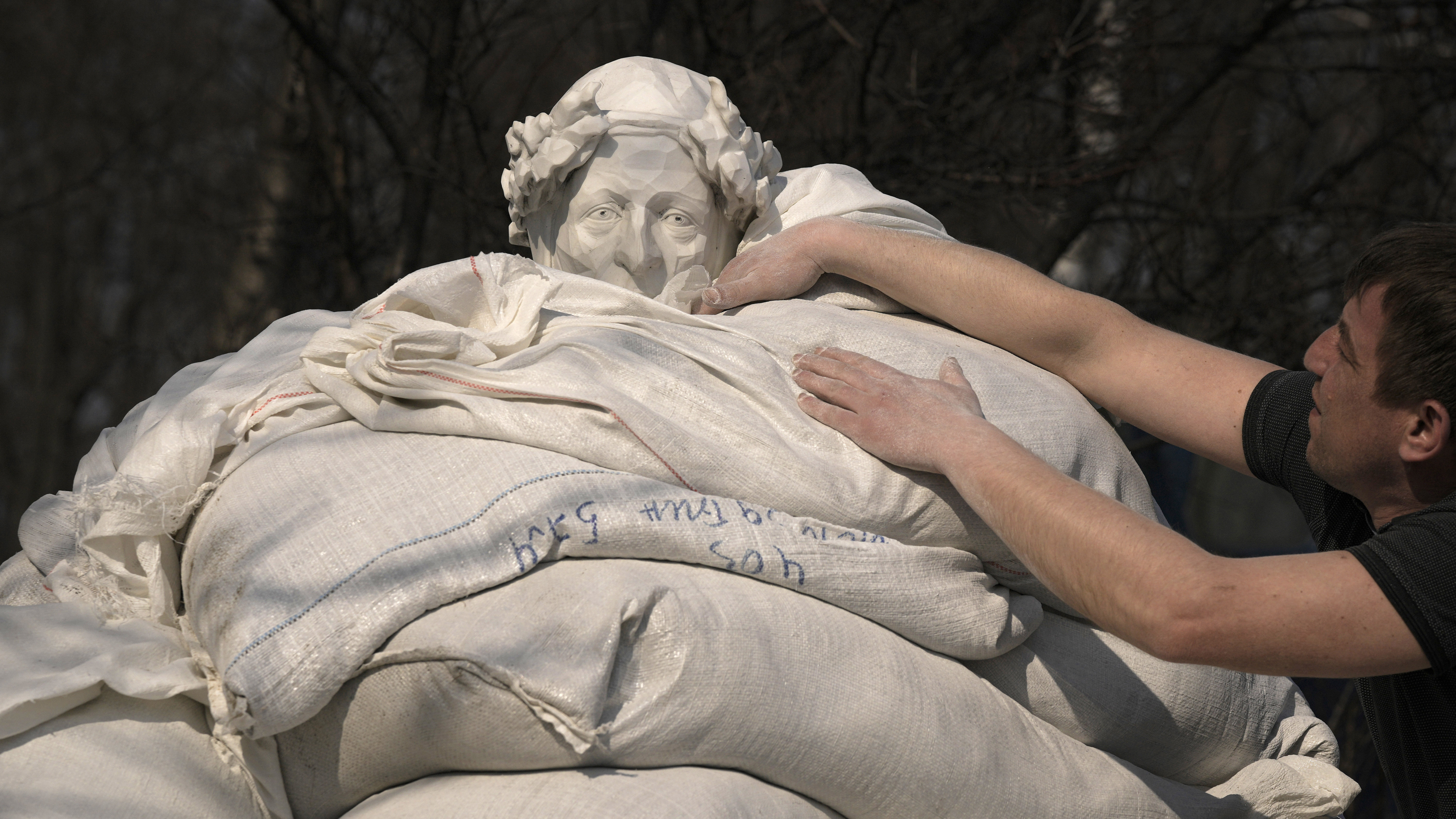 Municipal workers finish to cover the statue of Italian poet and philosopher Dante Alighieri with sandbags to protect it from potential damage from shelling, in Kyiv.