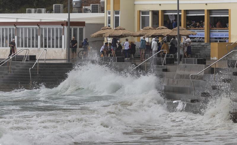 People flock to a waterfront cafe as wild seas pound Cronulla esplanade on Saturday morning.