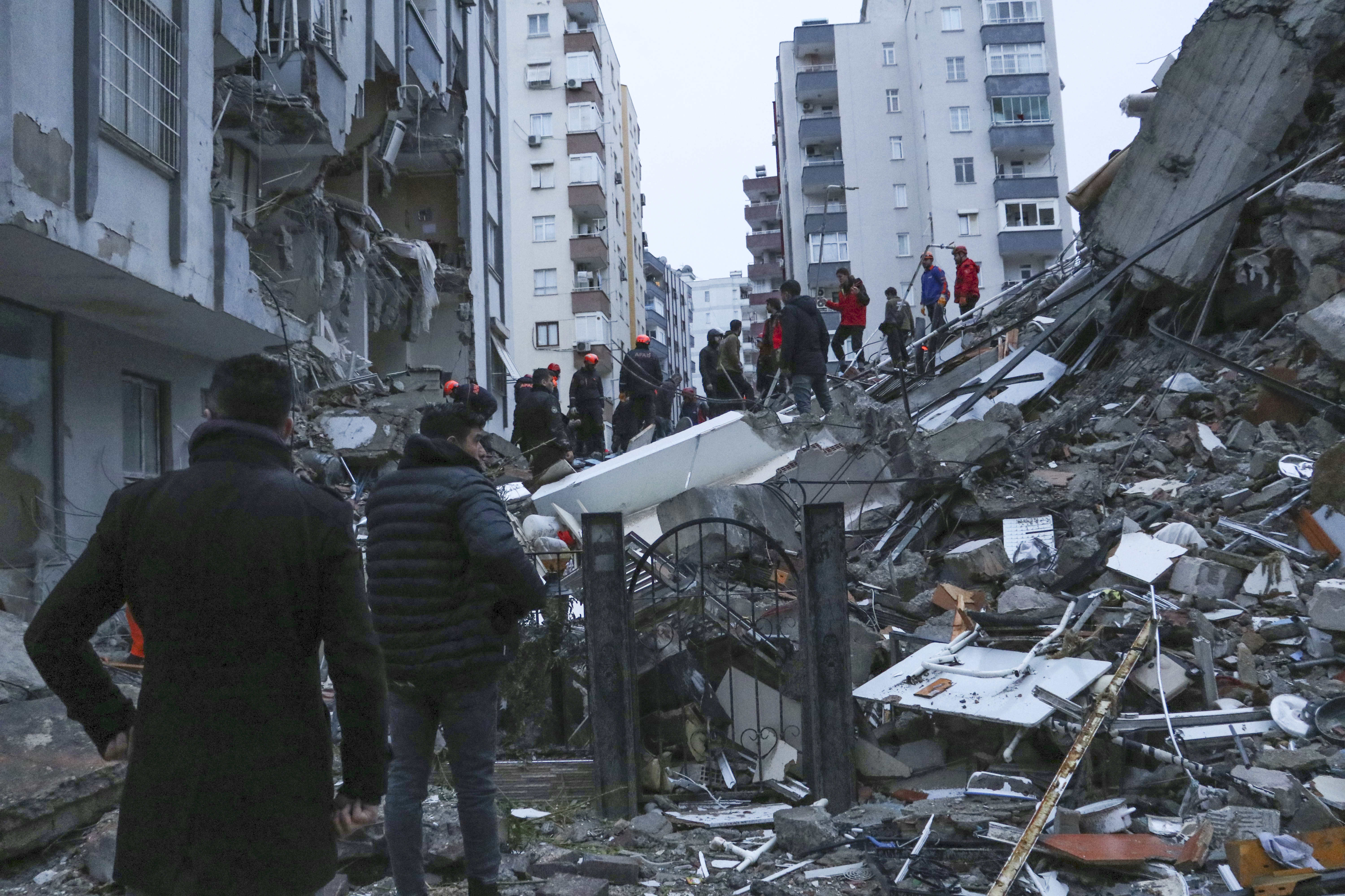 People and rescue teams try to reach trapped residents inside collapsed buildings in Adana, Turkey, Monday, Feb. 6, 2023 