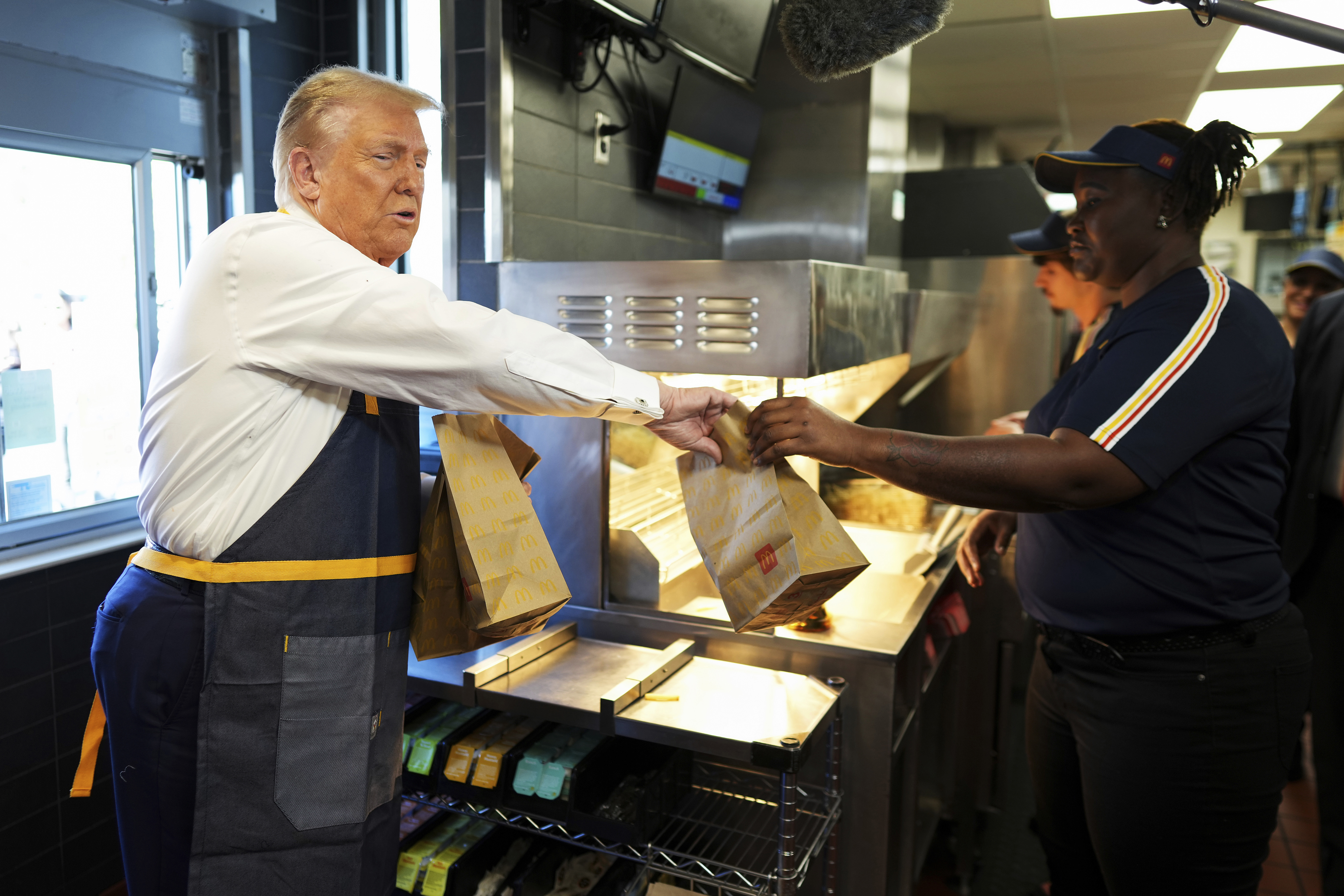 Un empleado entrega una orden al expresidente Donald Trump, candidato presidencial republicano, durante una visita a McDonald's en Feasterville-Trevose, Pensilvania, el domingo 20 de octubre de 2024. (Doug Mills/The New York Times vía AP, Pool)