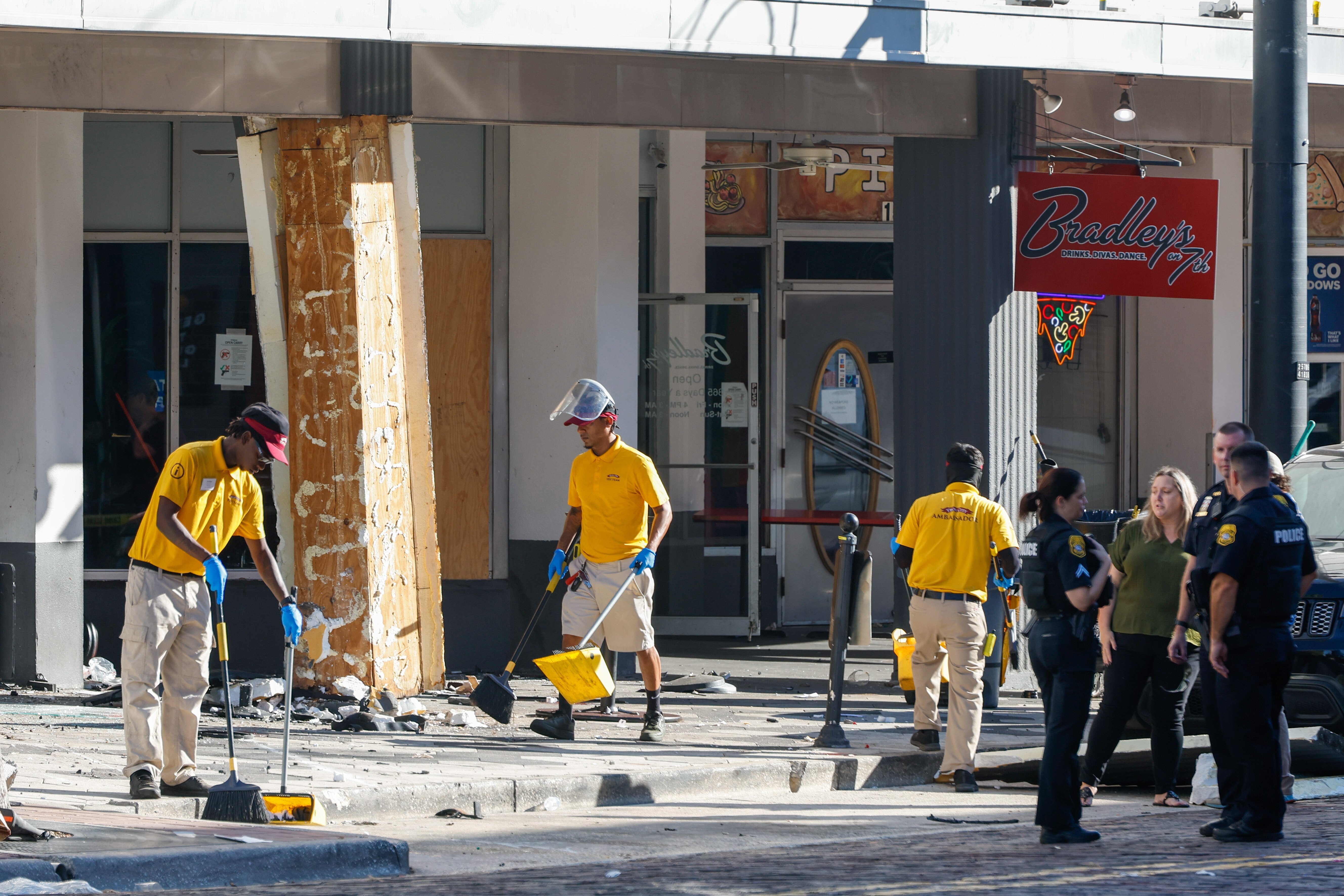 People clean up the damage from a car that crashed into a local business, while law enforcement investigate the scene on Saturday, Nov. 8, 2025, in Tampa, Fla. (Jefferee Woo/Tampa Bay Times via AP)