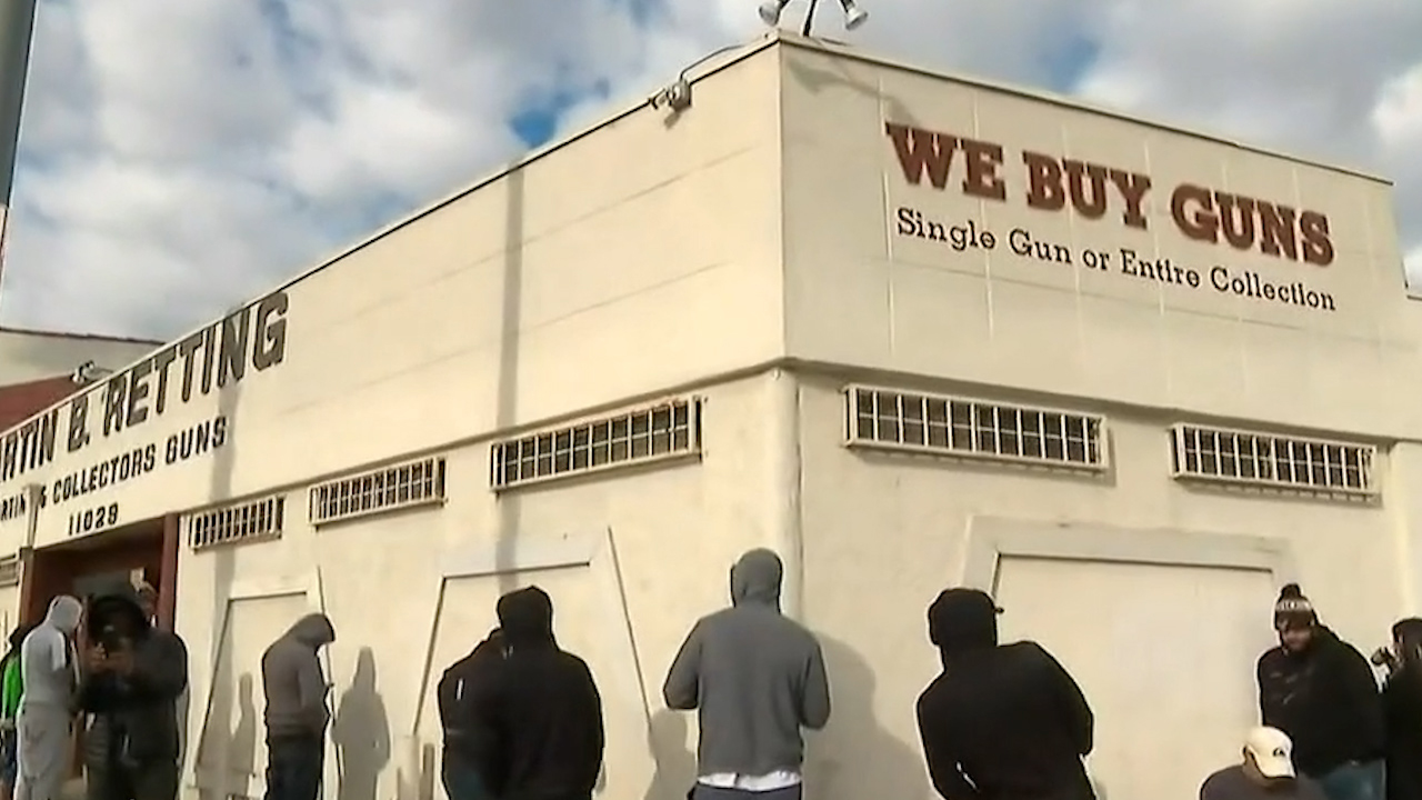 People in hooded sweatshirts wait in line outside an LA gun shop.