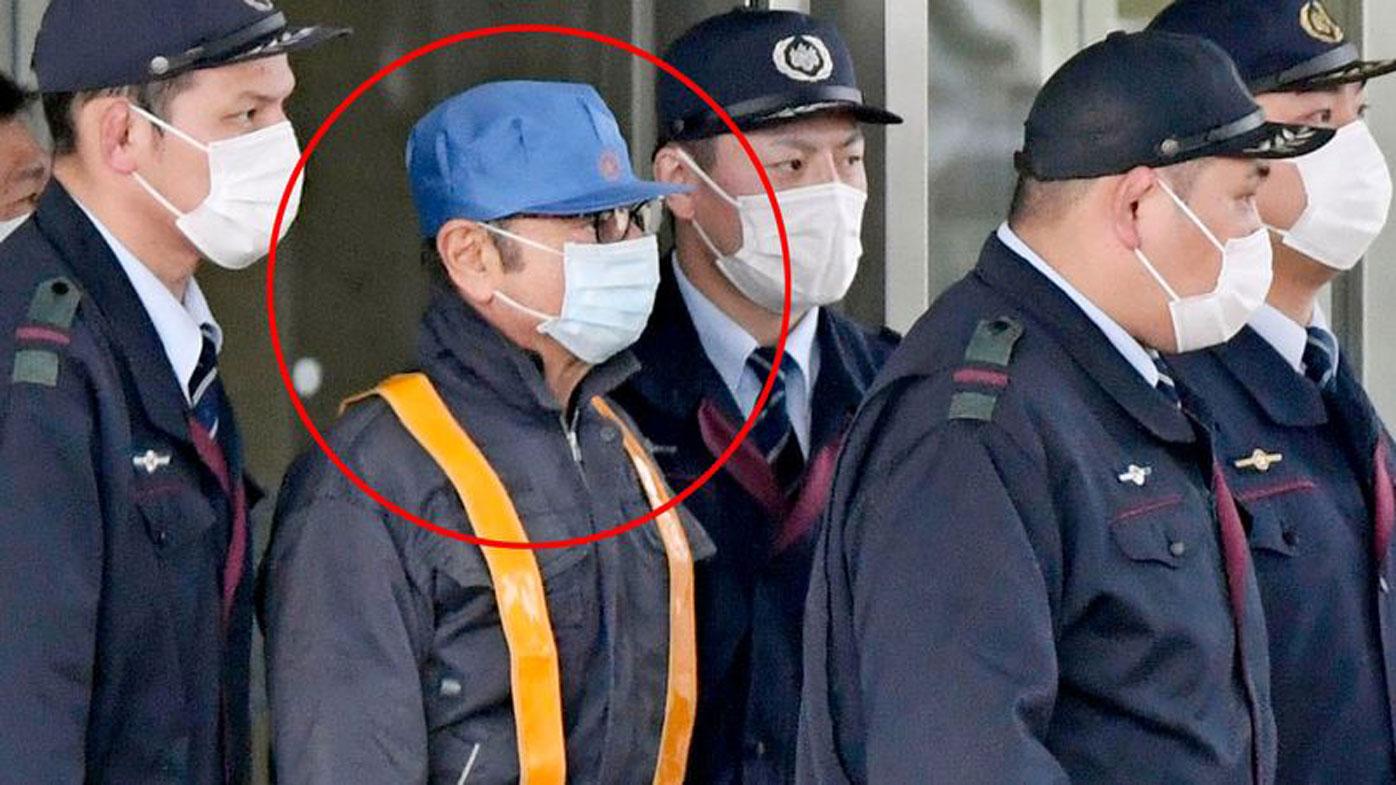 Former Nissan chairman Carlos Ghosn wears a costume of a blue hat and face mask as he walks free from the Tokyo Detention House, where he was held for 108 days