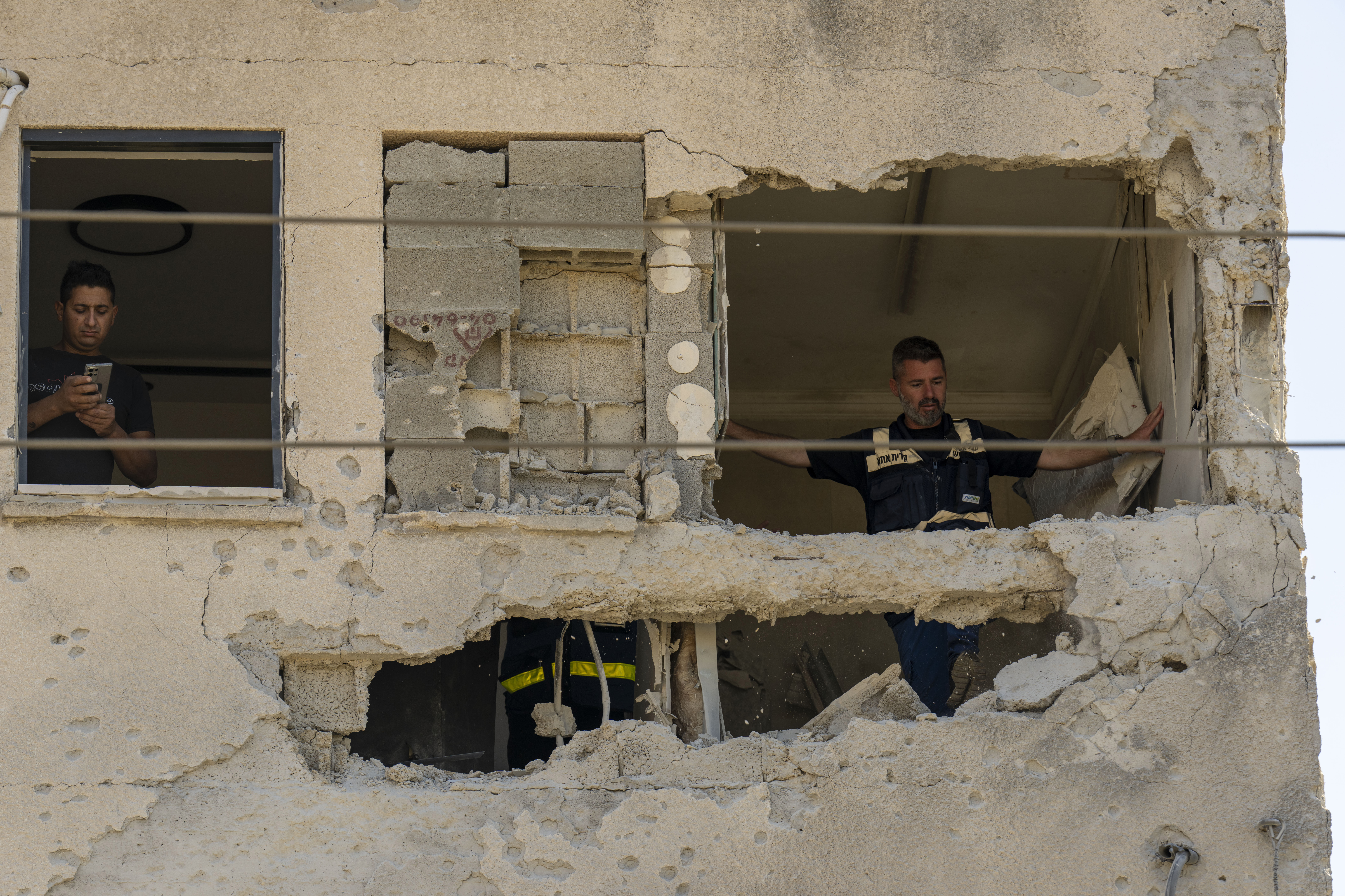 Municipality workers survey the damage to an apartment building struck by a rocket fired from Lebanon, in Kiryat Ata, northern Israel, Saturday, Oct. 19, 2024. 