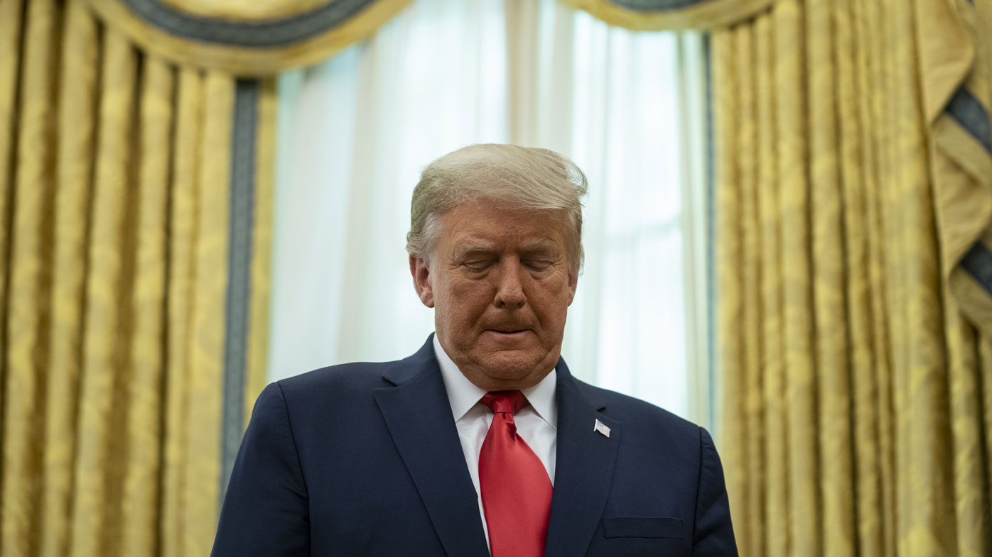 President Donald Trump listens during a ceremony to present the Presidential Medal of Freedom to former football coach Lou Holtz, in the Oval Office of the White House, Thursday, Dec. 3, 2020, in Washington