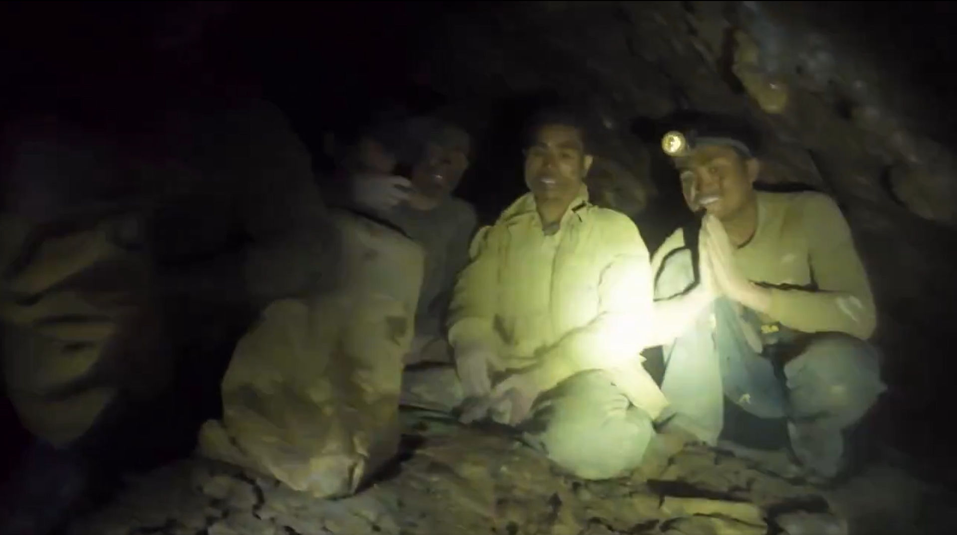The men could be seen sitting on a rocky ledge surrounded by floodwater and wearing headlamps.