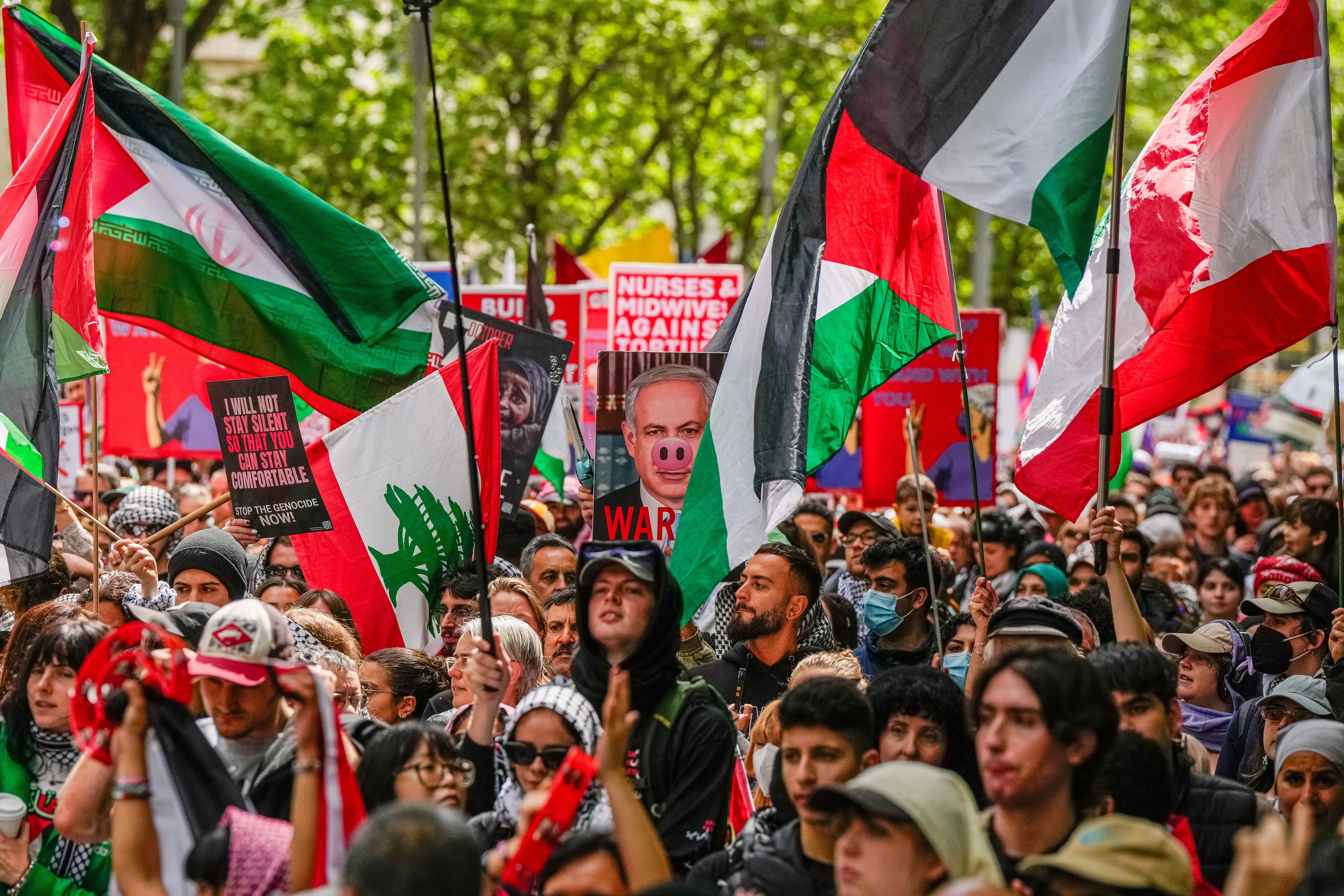 Pro-Palestine protesters waving Palestine flags as a protesters holds a placard of Benjamin Netanyahu on October 06, 2024 in Melbourne, Australia. 