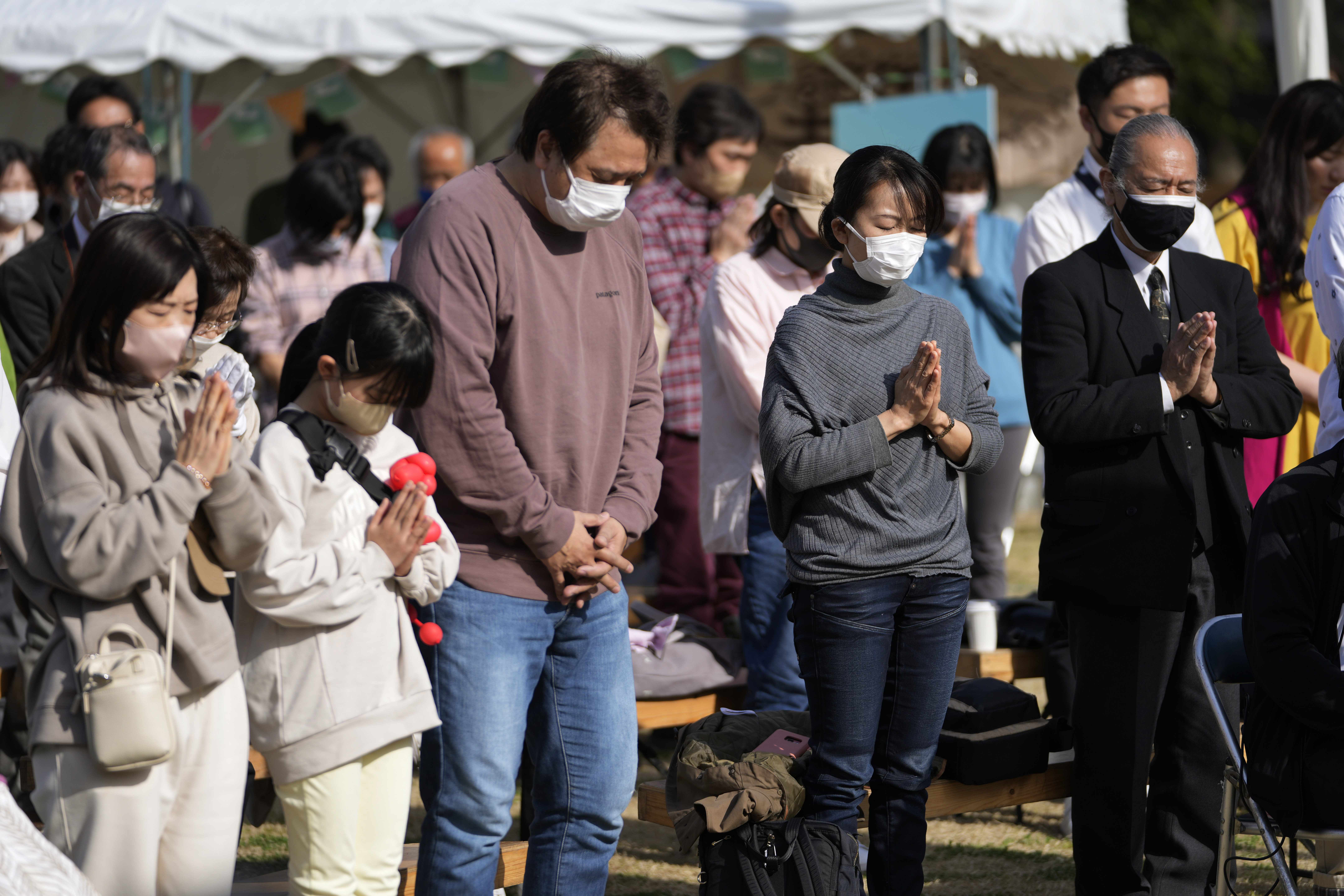 People pause for a minute of silence to commemorate the 311 disaster following an earthquake and tsunami in the Tohoku region 12 year ago, during an anniversary event at Hibiya Park in Tokyo, Saturday, March 11, 2023 