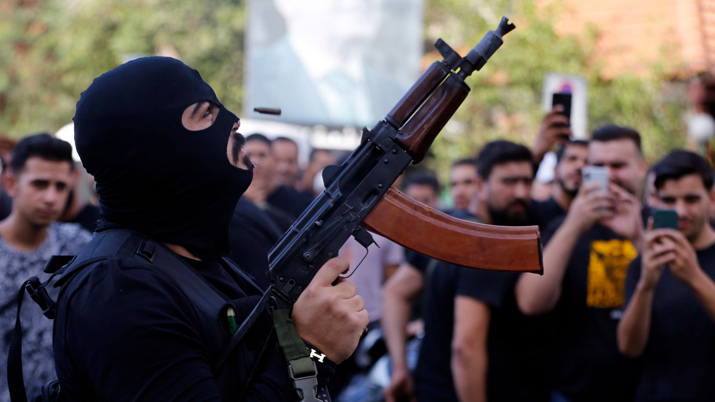 A man fires in the air during the funeral of three Hezbollah supporters