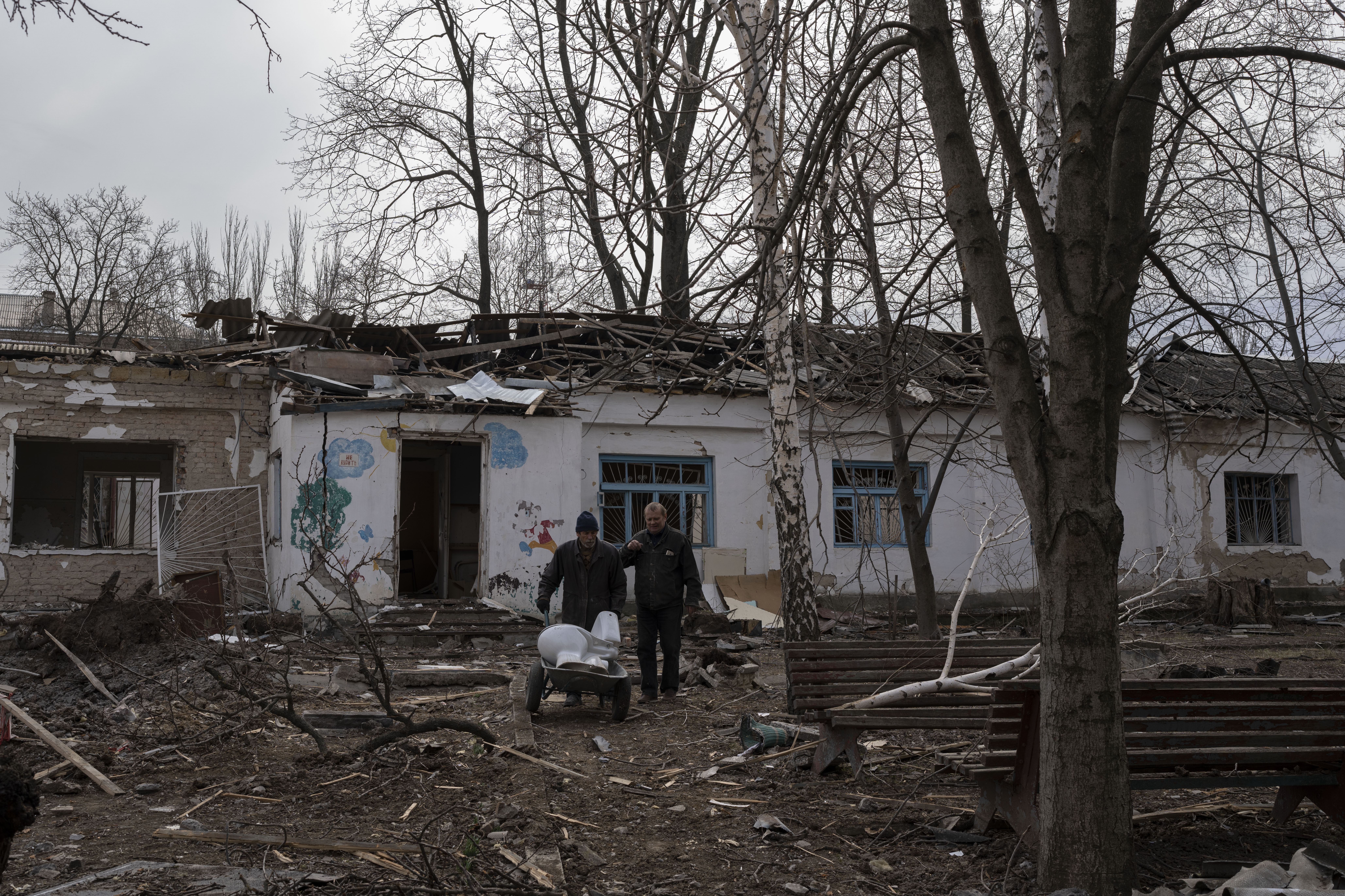 A man carries with a cart a toilet recovered from the debris of a Psychiatric hospital damaged by a Russian bombing earlier this week, in Mykolaiv, Ukraine, Friday, 25, 2022.(AP Photo/Petros Giannakouris)