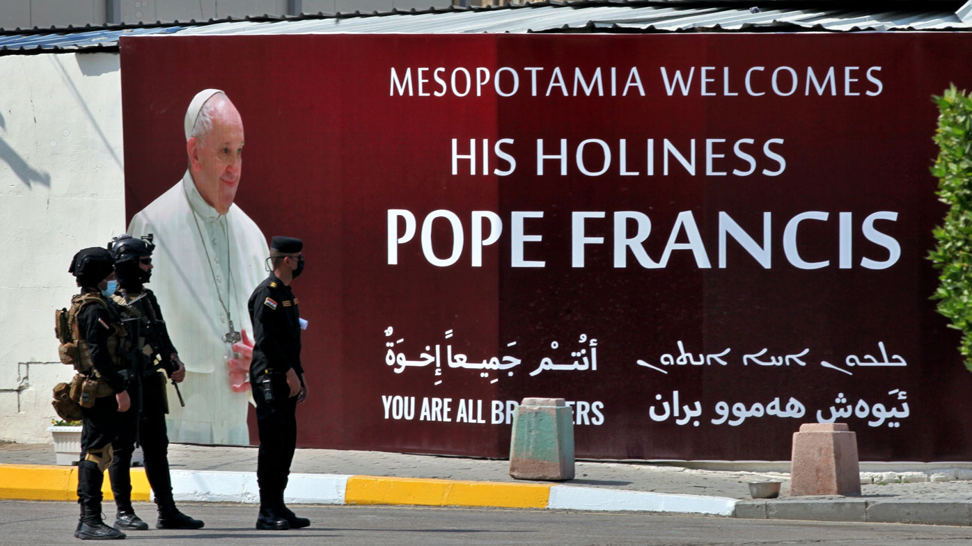 Iraqi security forces stand guard by a mural depicting Pope Francis outside of Our Lady of Salvation Church in Baghdad, Iraq, Friday, March 5, 2021