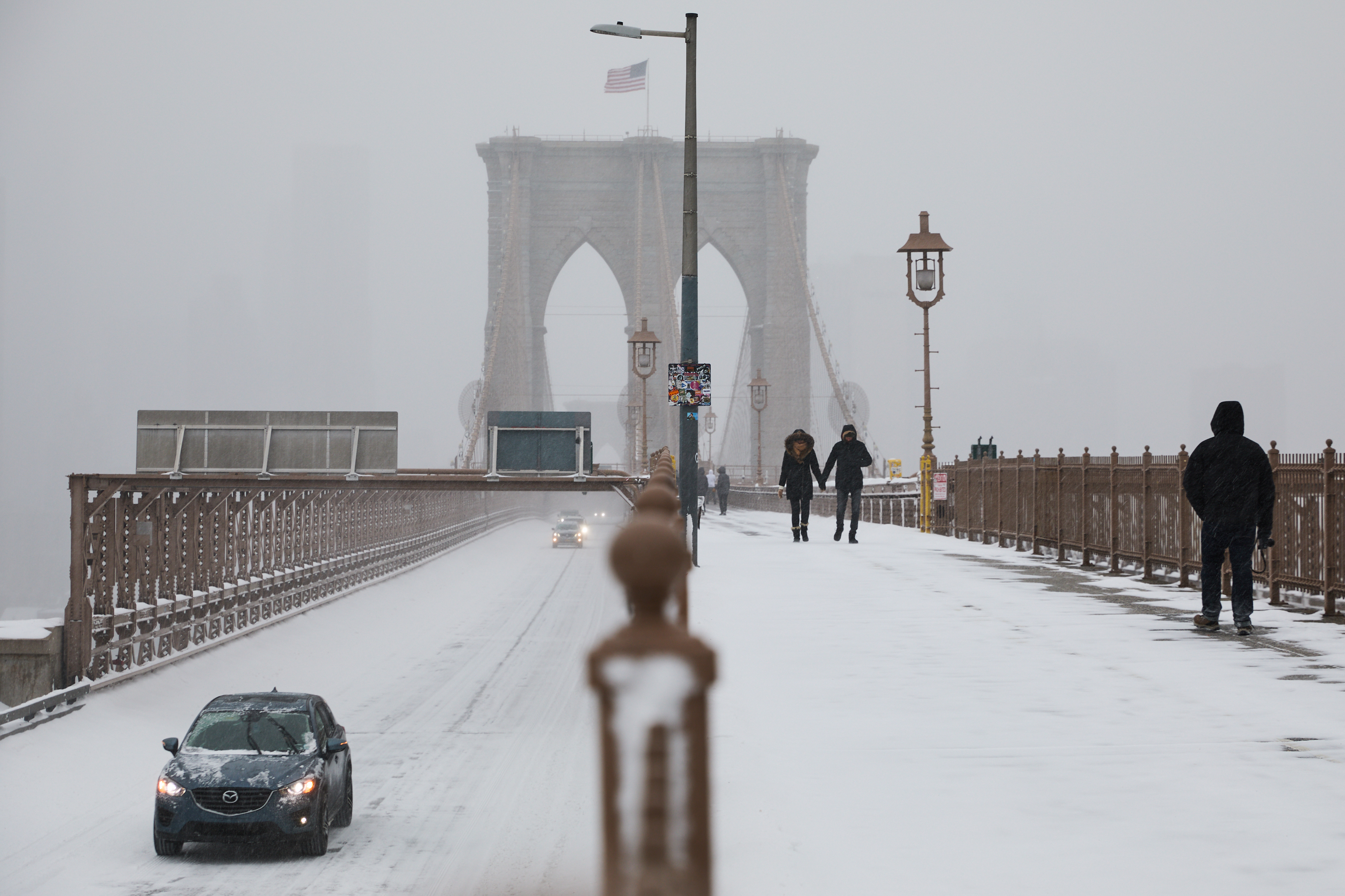 Drivers and pedestrians traverse the Brooklyn Bridge during a winter storm, Sunday, Jan. 25, 2026, in New York.  