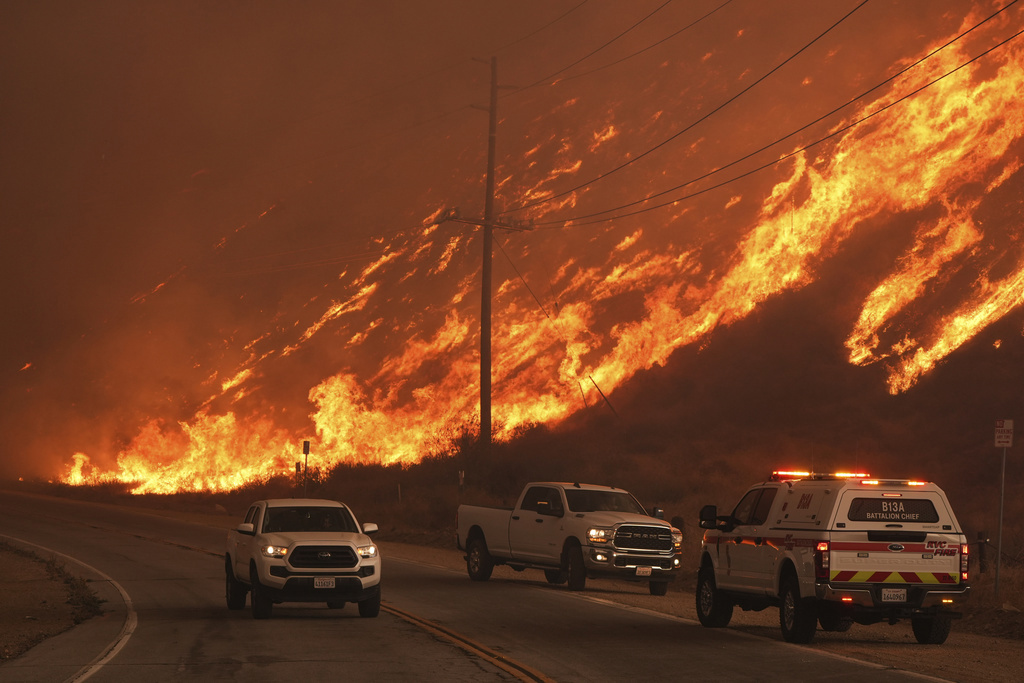 Firefighters monitor flames caused by the Hughes Fire along Castaic Lake in Castaic, California.