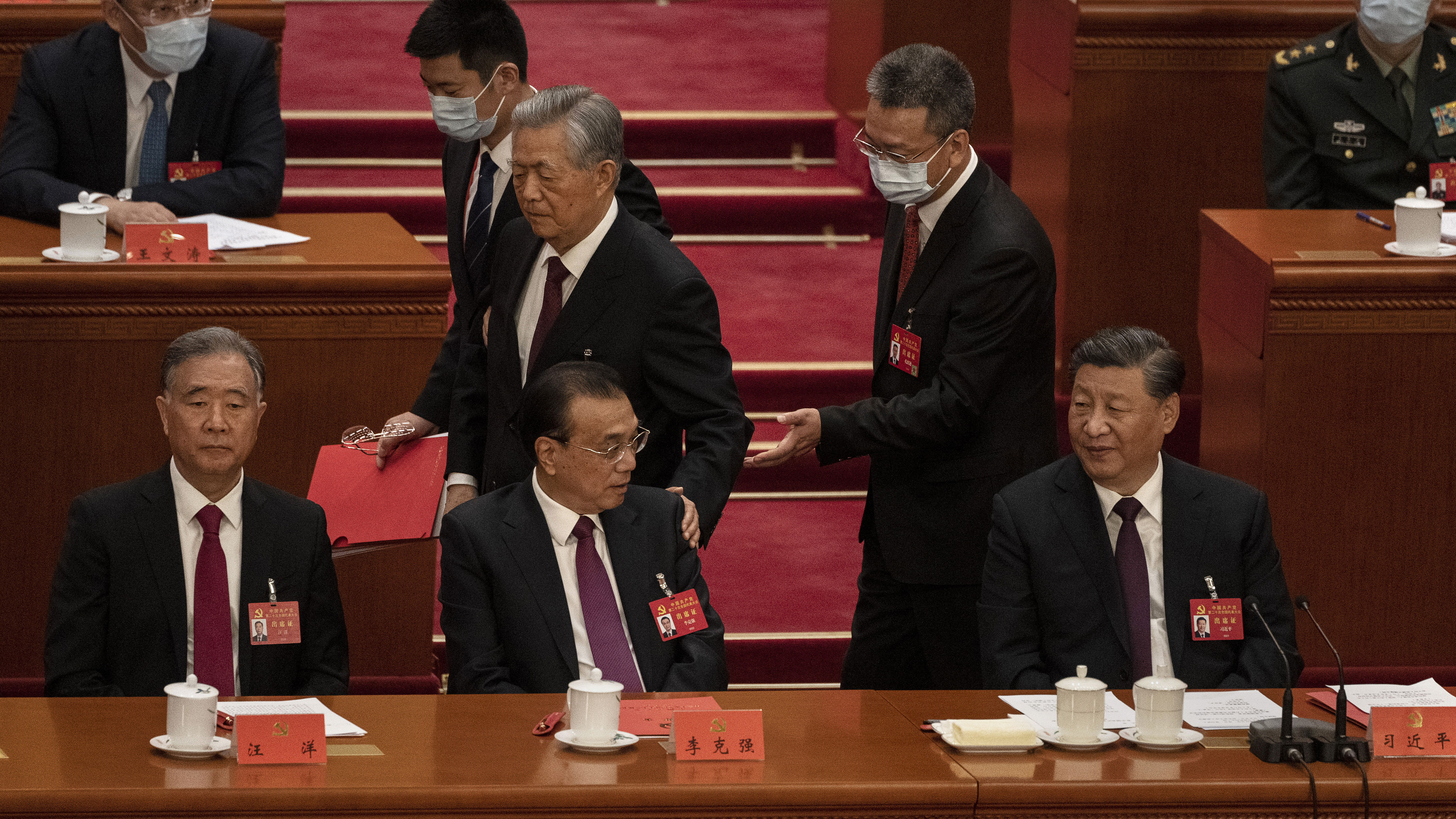 Chinese President Xi Jinping and Premier Li Keqiang, left, and Politburo member Wang Yang look on as former President Hu Jintao, centre, speaks to them as he is helped to leave early from the closing session of the 20th National Congress of the Communist Party of China.