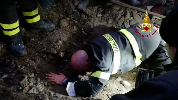 The firefighter clears the opening of dirt and debris before reaching in. 