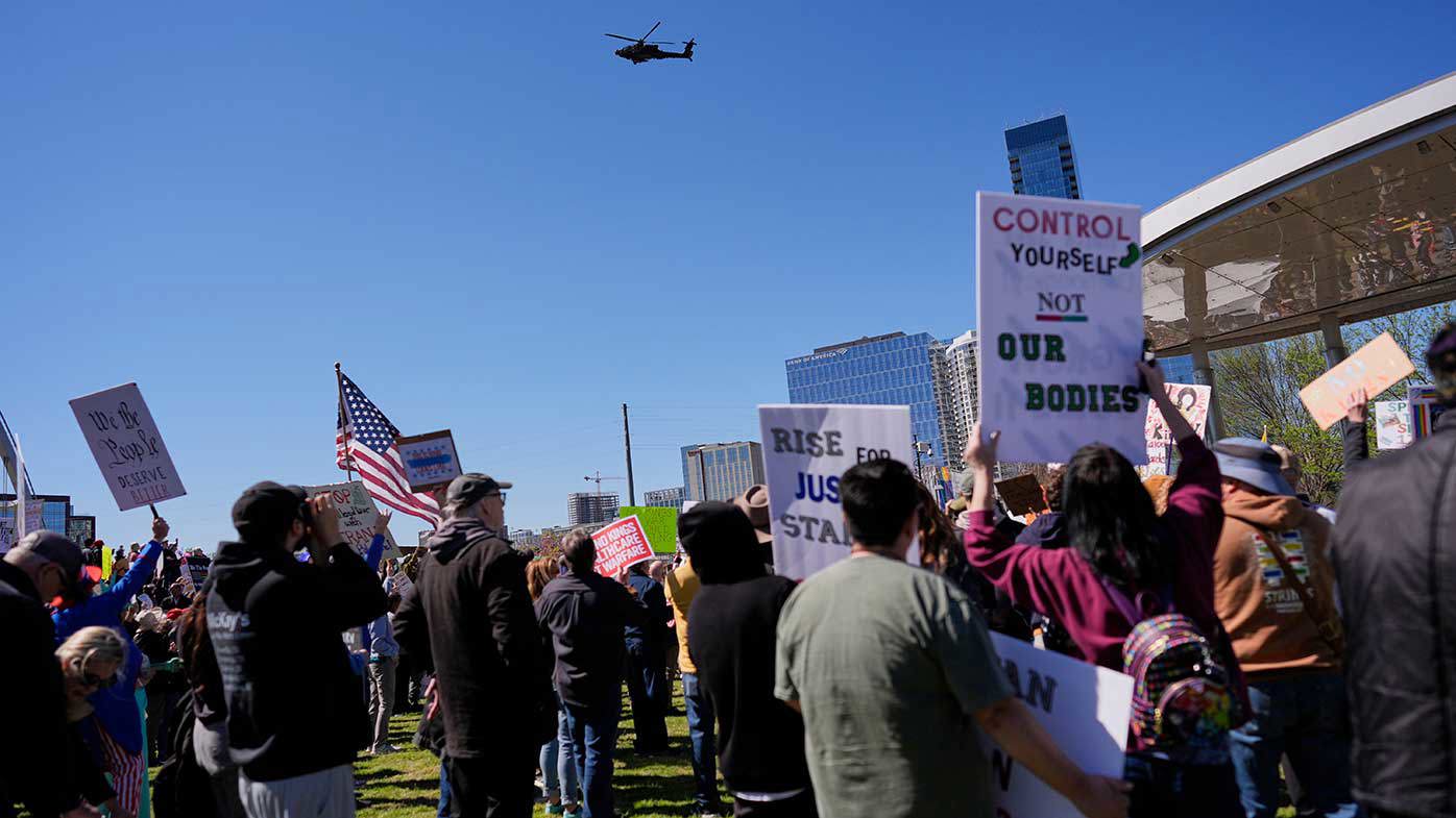 An Apache helicopter flies about the Nashville No Kings protest.