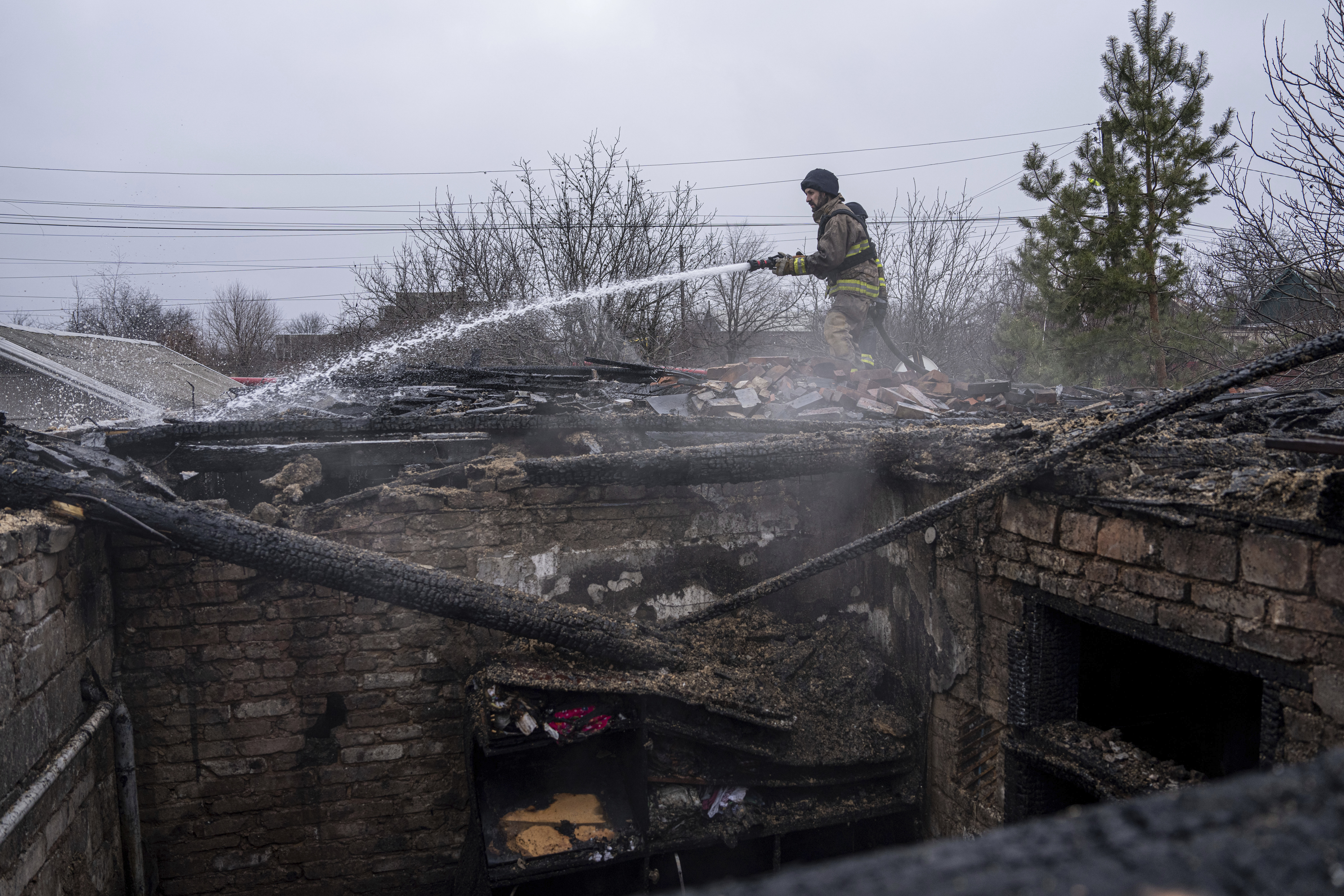 A rescue worker puts out the fire of a house which was destroyed by Russian shelling in Kostiantynivka, Ukraine, Wednesday, March 8, 2023. (AP Photo/Evgeniy Maloletka)