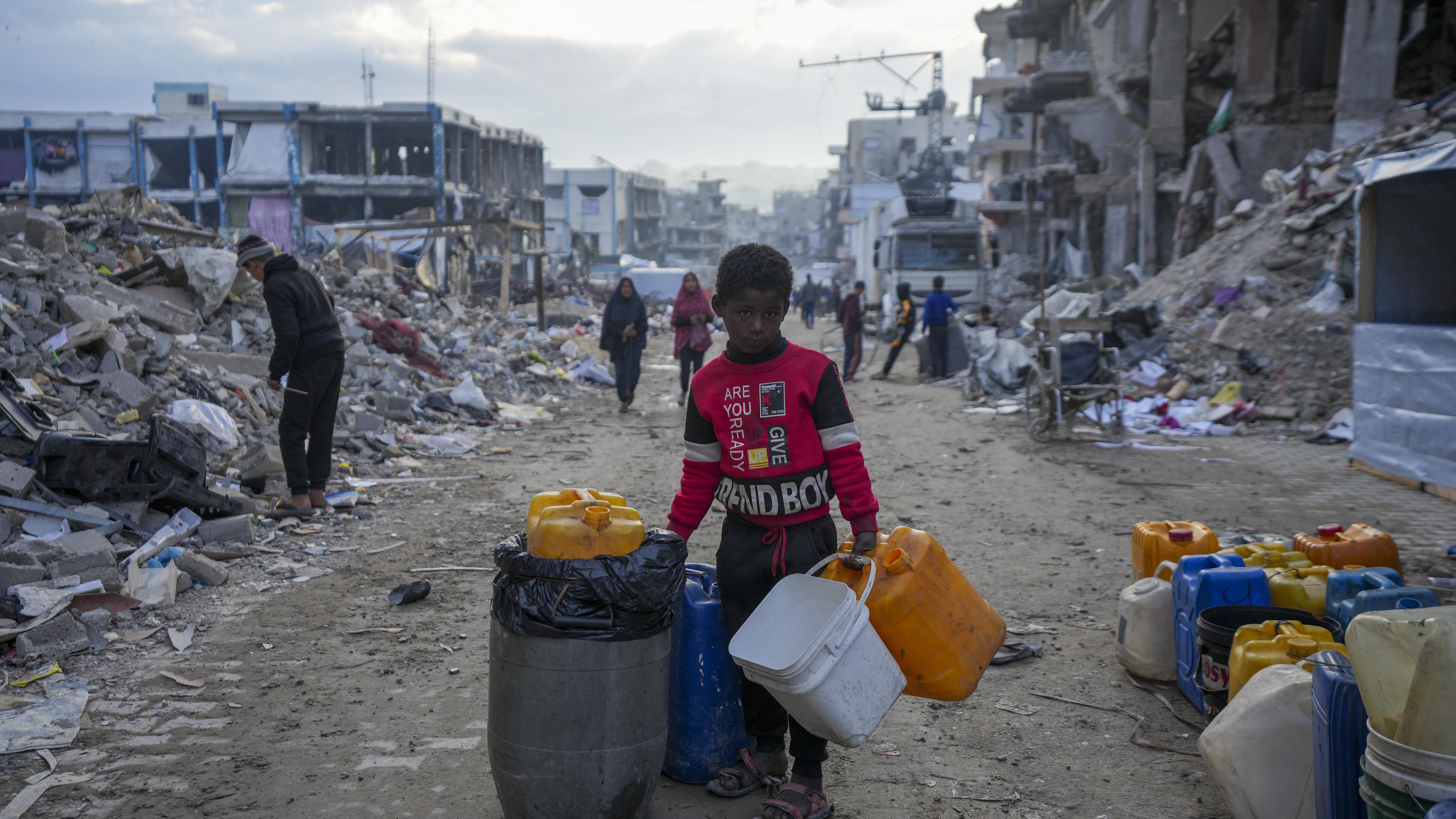 A young Palestinian kid carries jerri cans along the destruction caused by the Israeli air and ground offensive in Jabaliya, Gaza Strip.