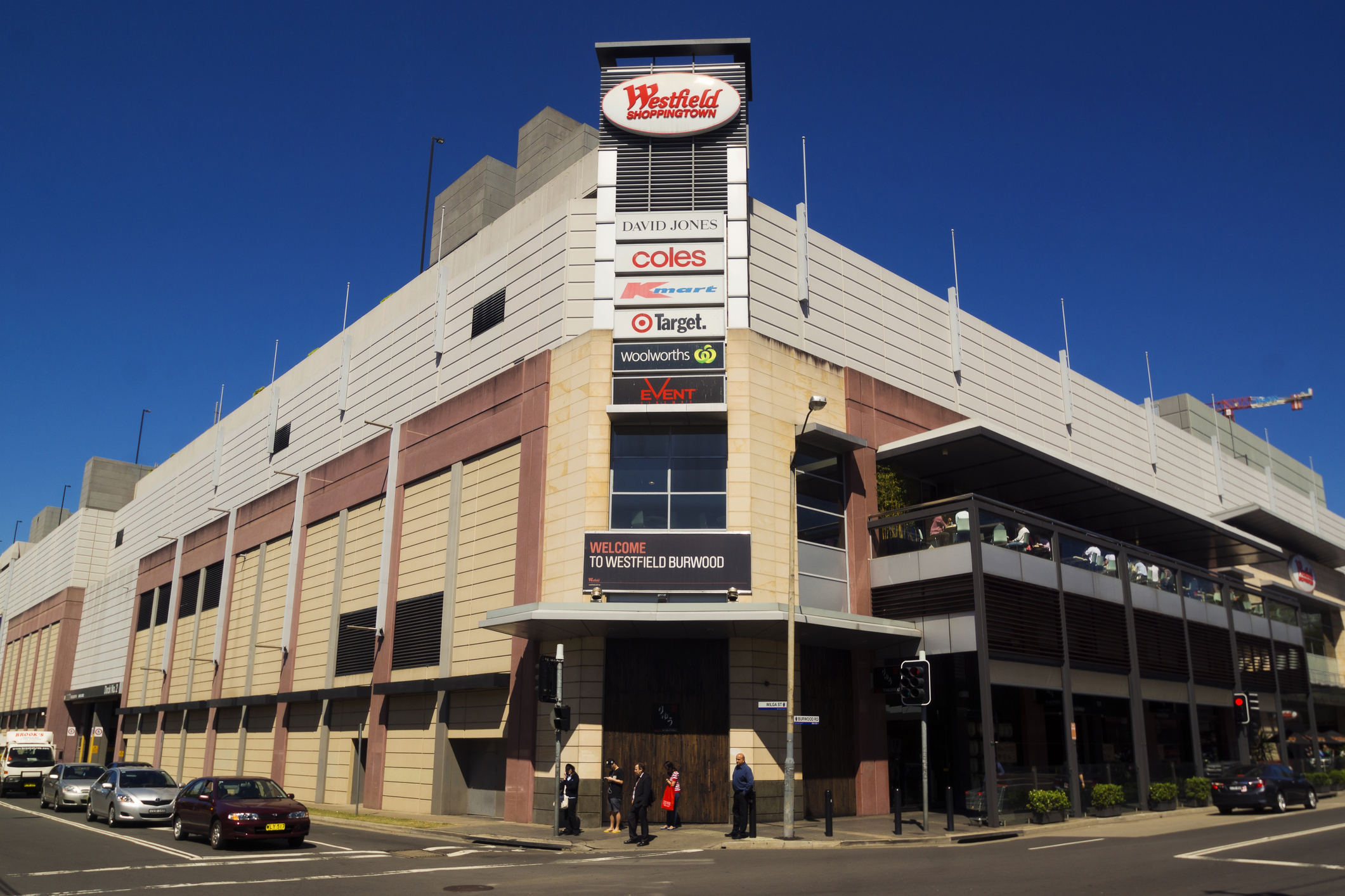 Sydney, Australia - October 2, 2014: Pedestrians and traffic waiting around an intersection beside Westfield Burwood. Westfield is a large chain of shopping malls, with over a hundred locations worldwide.
