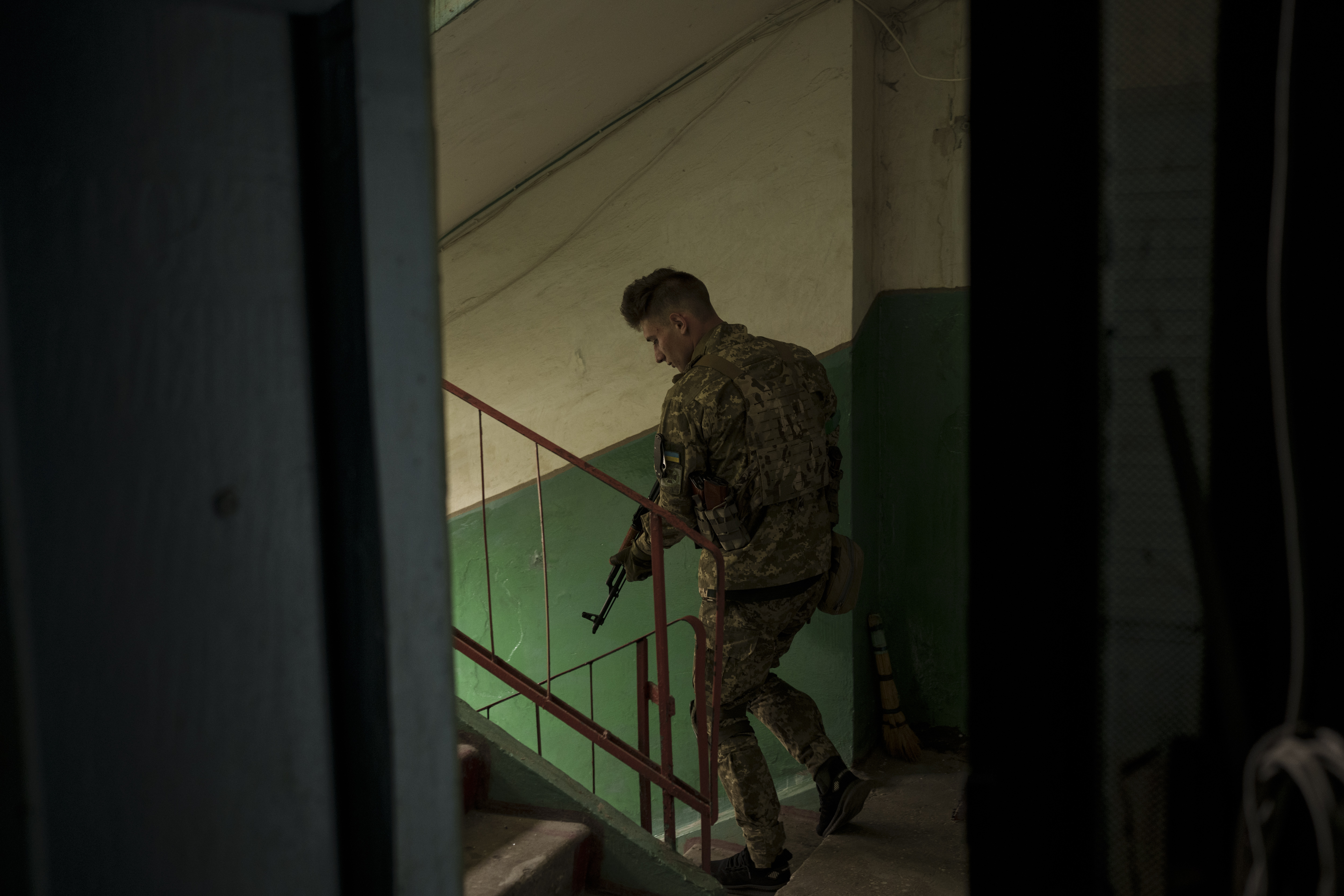 A Ukrainian serviceman walks inside a building after searching the apartment of a man suspected of being a Russian collaborator in Kharkiv, Ukraine.