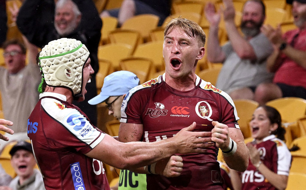 Tate McDermott of the Reds is congratulated by teammates after scoring a try.