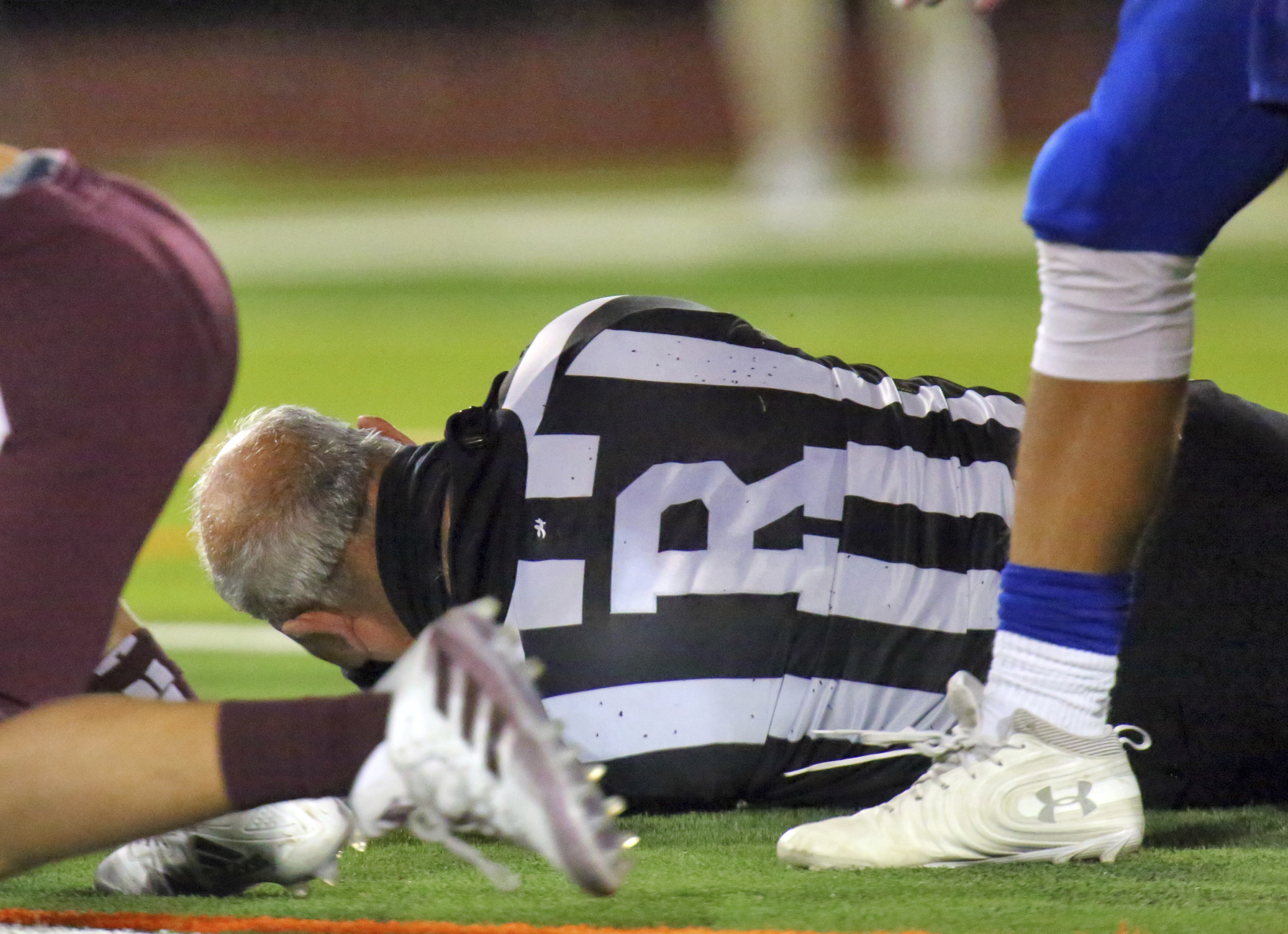 Football referee Fred Gracia lays on the ground right after being charged by Edinburg High's Emmanuel Duron.