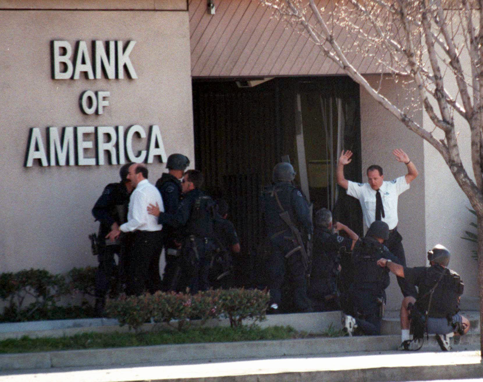 A bank employee holds up his hands as Los Angeles Police and SWAT units search for more robbery suspects inside the Bank of America