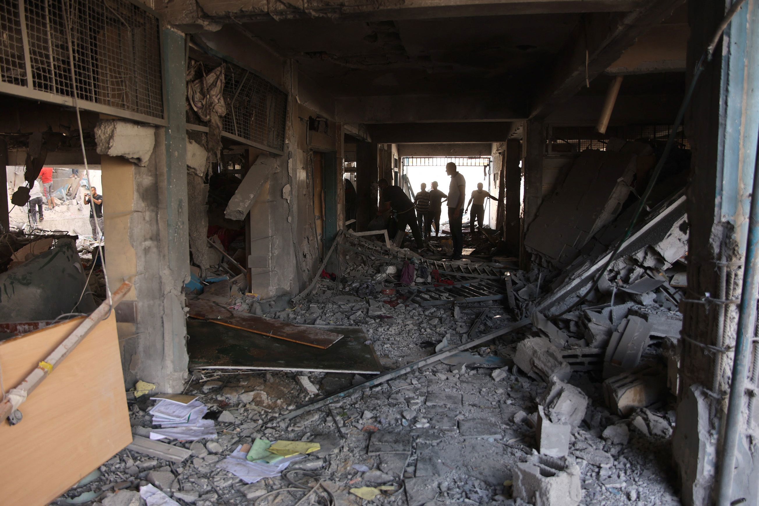 Palestinians inspect the damage at the site of an Israeli strike on a school.