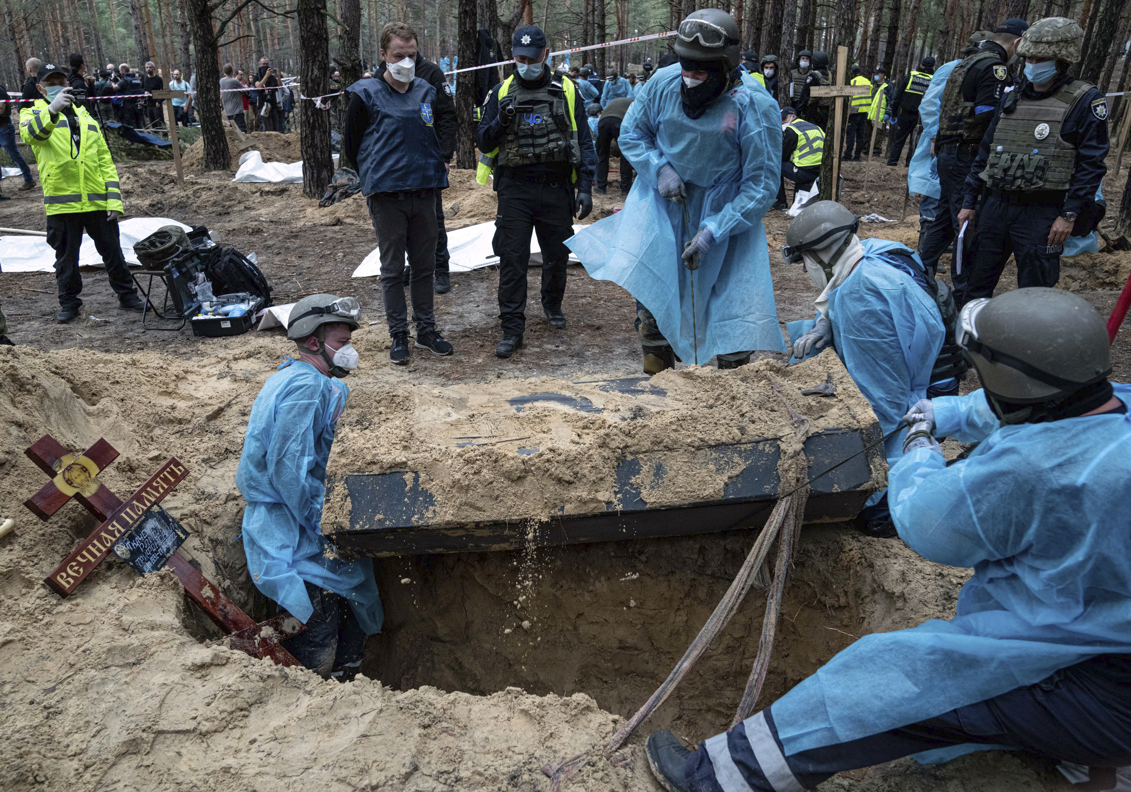 Emergency workers move a body during the exhumation in the recently retaken area of Izium, Ukraine, Friday, Sept. 16, 2022. 