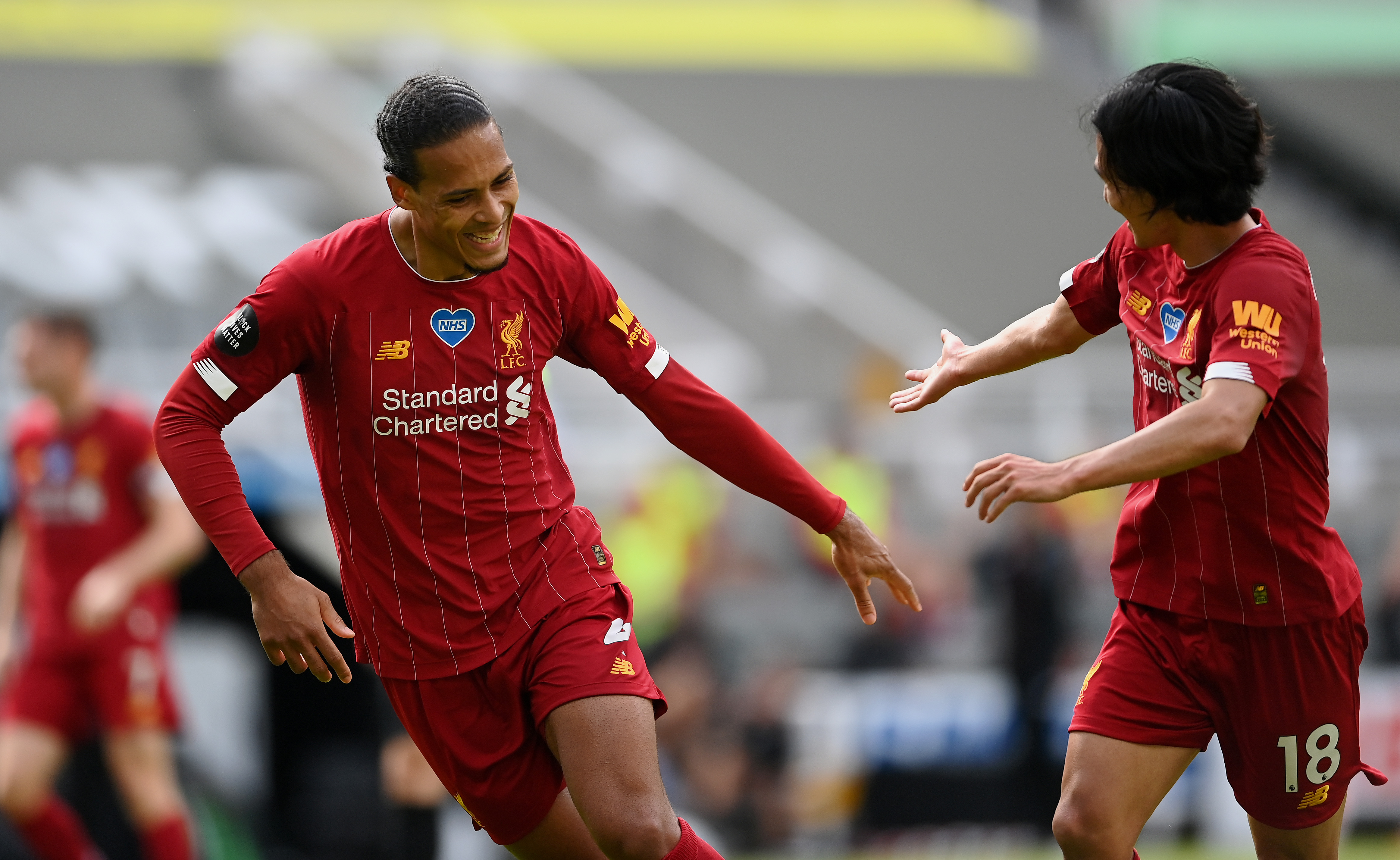 Virgil van Dijk of Liverpool celebrates with teammate Takumi Minamino.