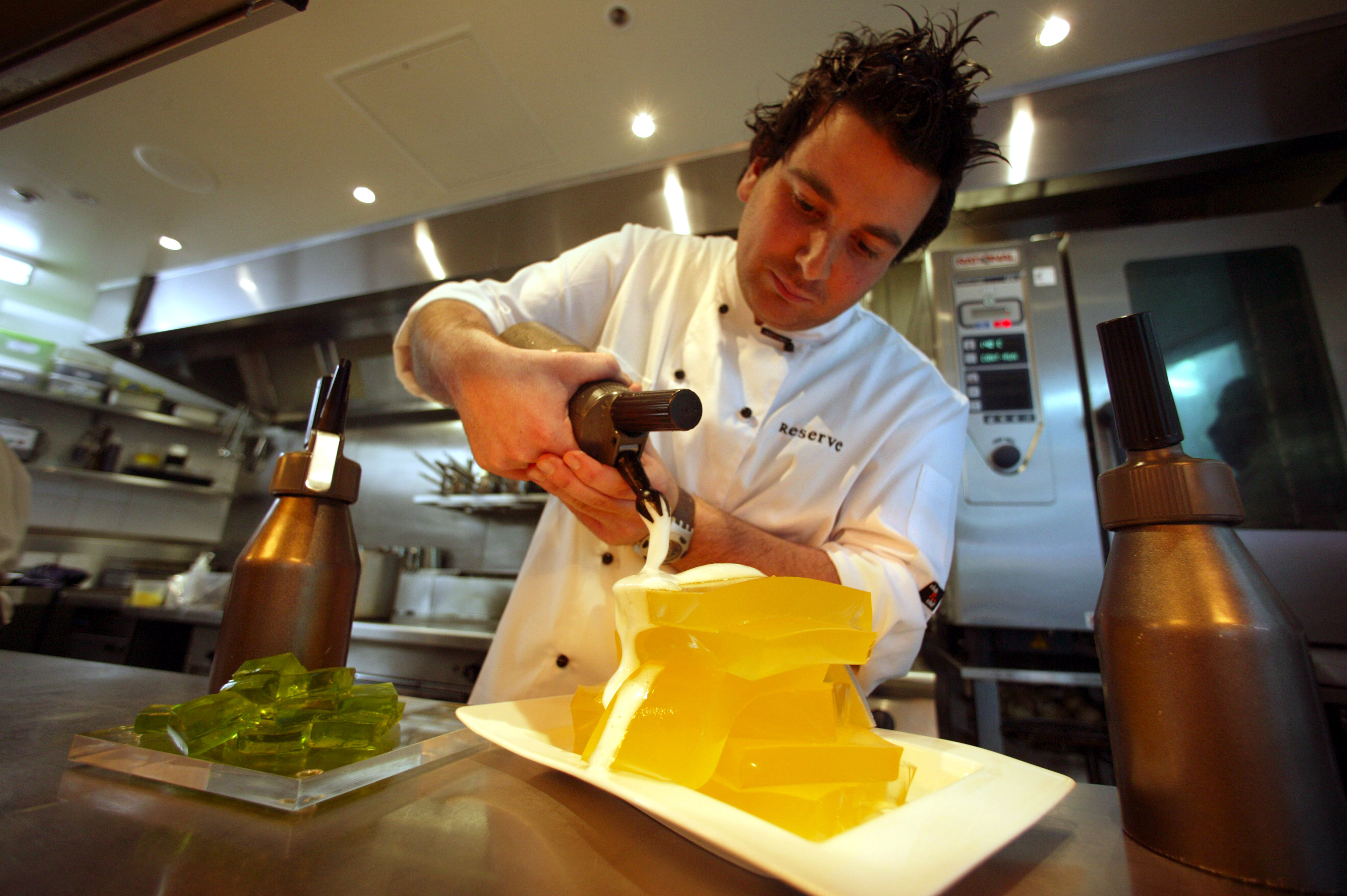 In this 2003 file photo, George Calombaris applies the finishing touches to a gin and tonic jelly with champagne foam.