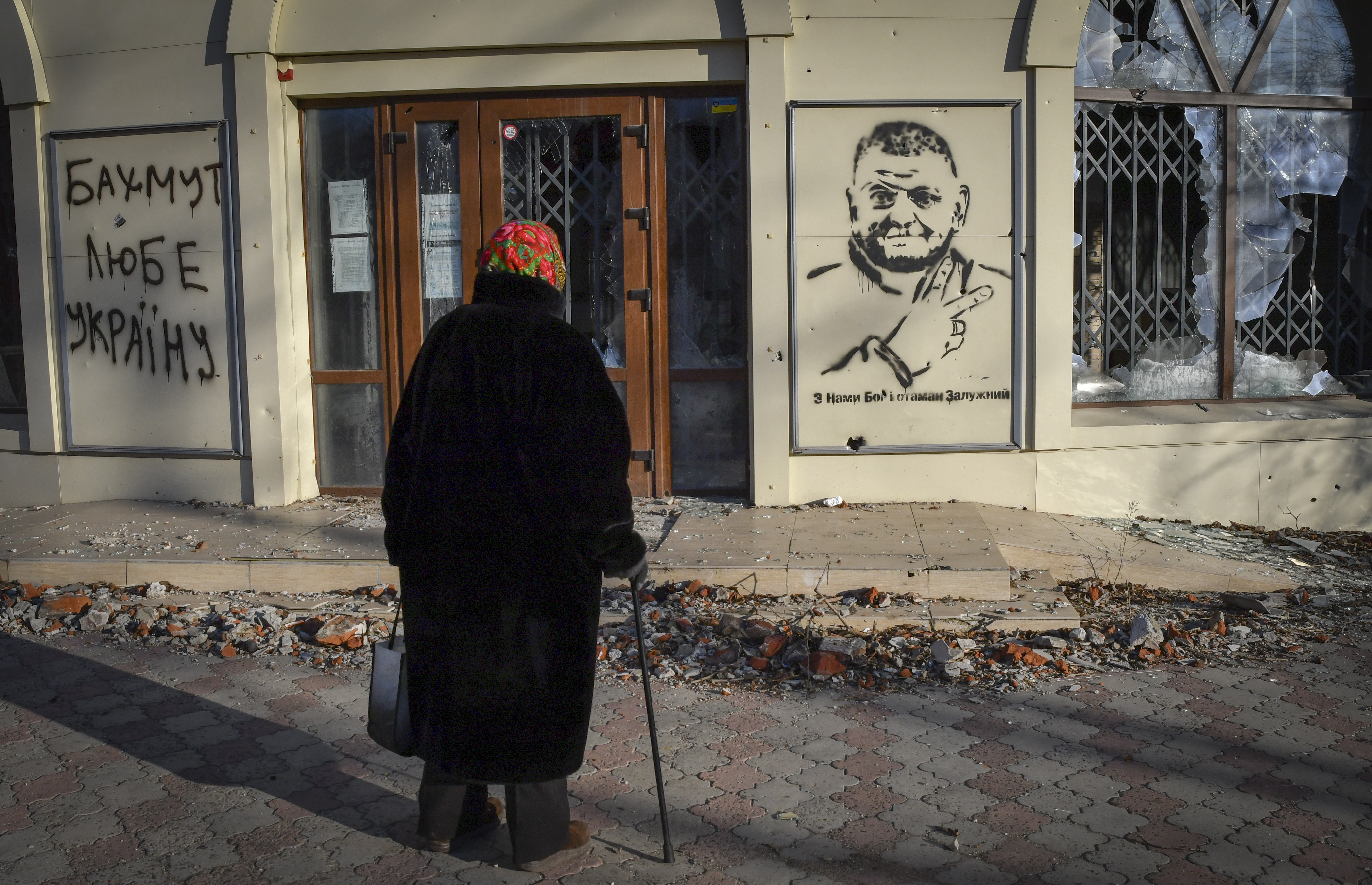 Una anciana mira un grafiti que representa al general Valery Zaluzhny, jefe de las fuerzas armadas de Ucrania y escribe "Dios está con nosotros y el comandante Zaluzhny" en el sitio de las batallas más duras con los invasores rusos en Bakhmut, Ucrania, el martes 20 de diciembre de 2022