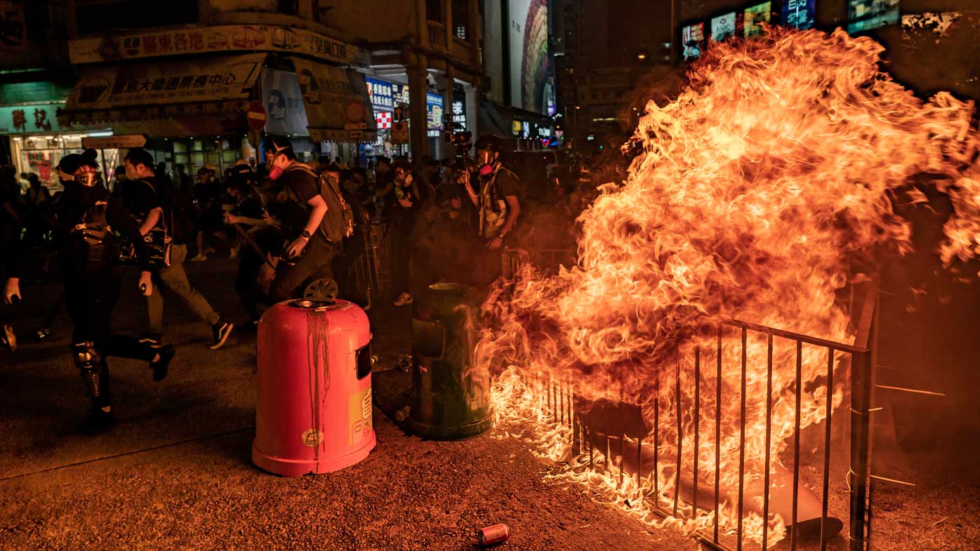 Pro-democracy protesters run behind a burning barricade after police charged toward them during a demonstration in Mongkok district on October 1, 2019 in Hong Kong.