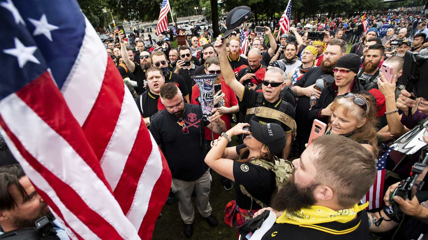 Members of the Proud Boys and other right-wing demonstrators plant a flag in Tom McCall Waterfront Park during a rally in Portland, Oregon.