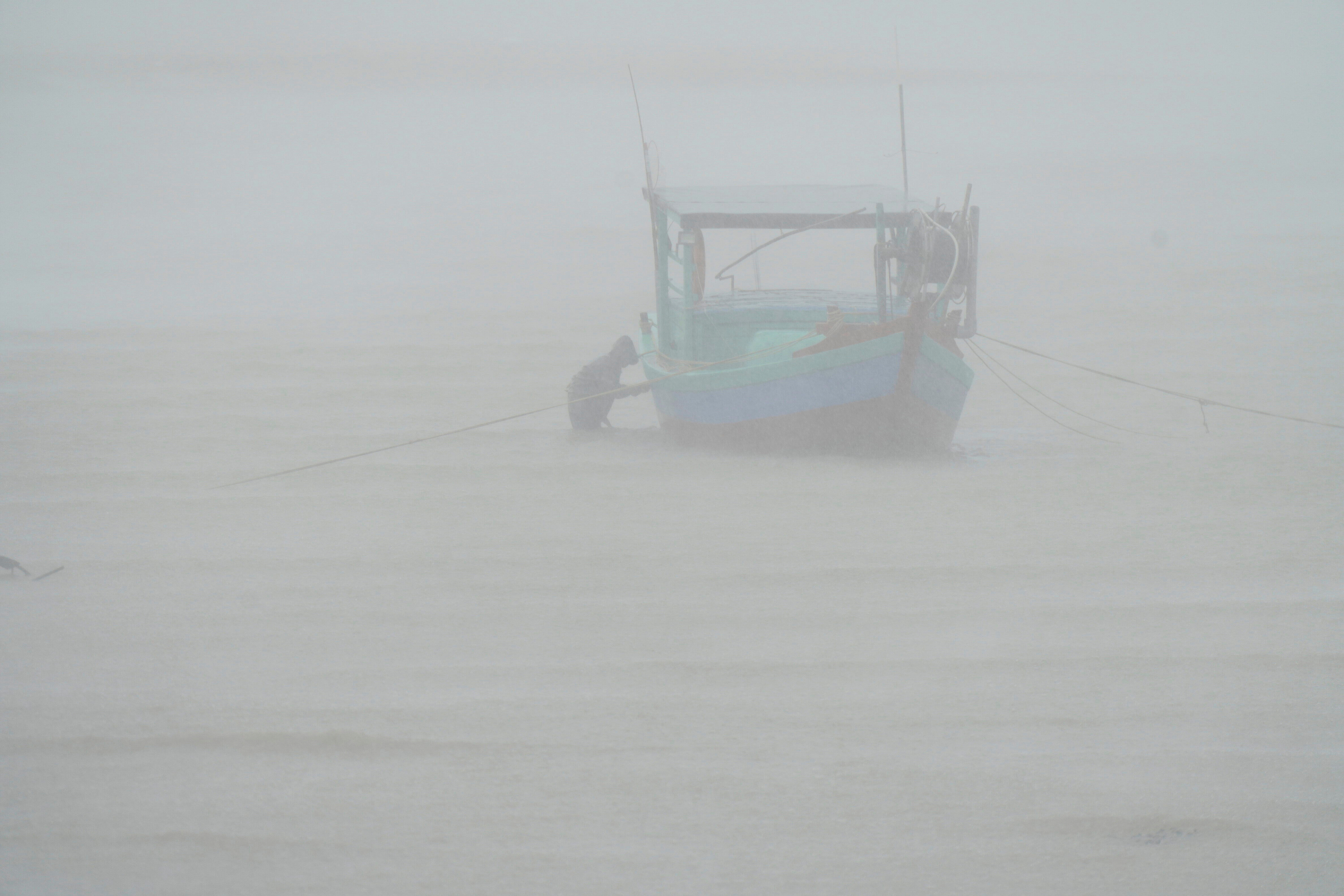 A fisherman checks his boat in the rain in Ha Tinh province, Vietnam, as Typhoon Kajiki approached.