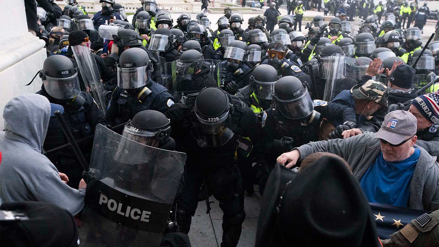 La policía del Capitolio de EE. UU. hace retroceder a los manifestantes que intentan ingresar al edificio del Congreso.