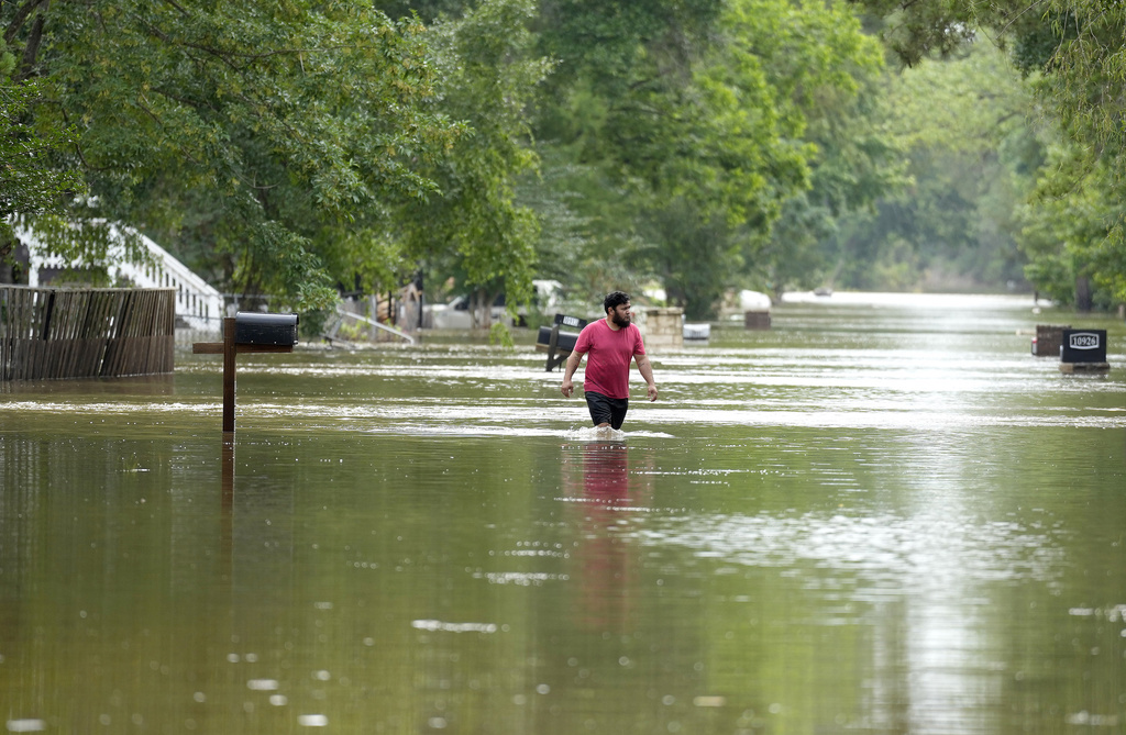 CORRECTS CITY TO WOODLOCH NOT WOODLOCK - A man walks through floodwaters on River Oaks Drive, Saturday, May 4, 2024, in Woodloch, Texas. (Karen Warren/Houston Chronicle via AP)