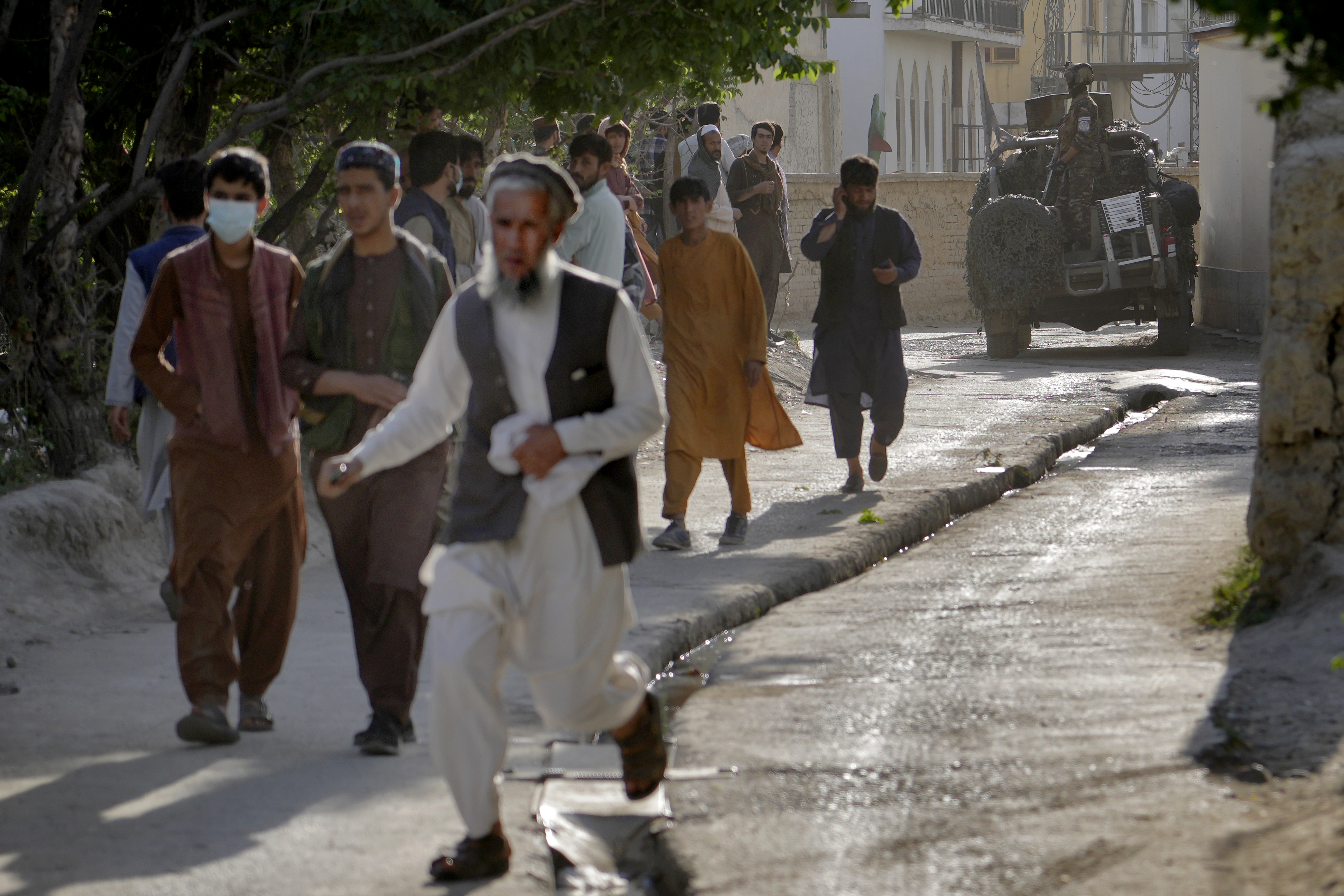 People leave the site of an explosion as a Taliban fighter stands guard in Kabul, Afghanistan, Friday, April 29, 2022. A powerful explosion ripped through a mosque in the Afghan capital of Kabul on Friday, killing at least 10 people and wounding 20, a Taliban spokesman said. (AP Photo/Ebrahim Noroozi)