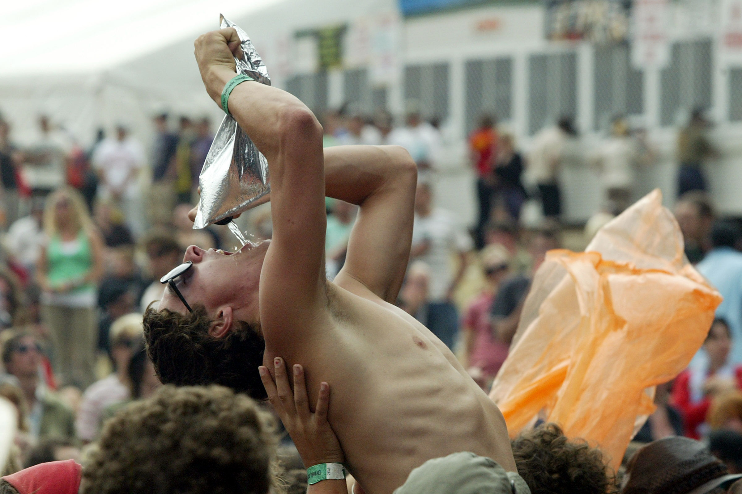 Festival-goer crowdsurfing and drinking cask wine at the same time. 