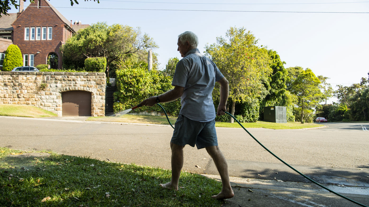 A man waters his garden with a hose in Sydney's Vaucluse. 