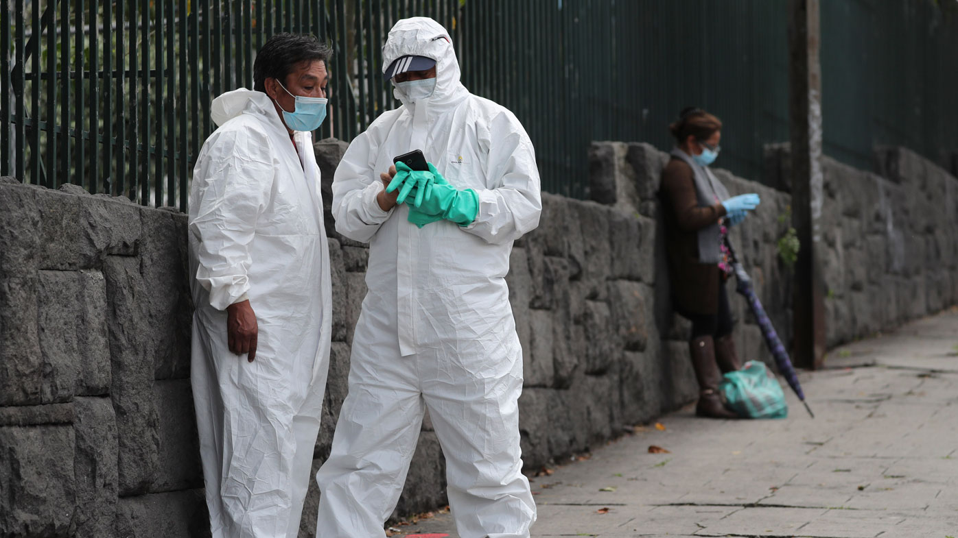Men wearing biological safety suits stand outside Carlos Andrade Marin Hospital in Quito, Ecuador.