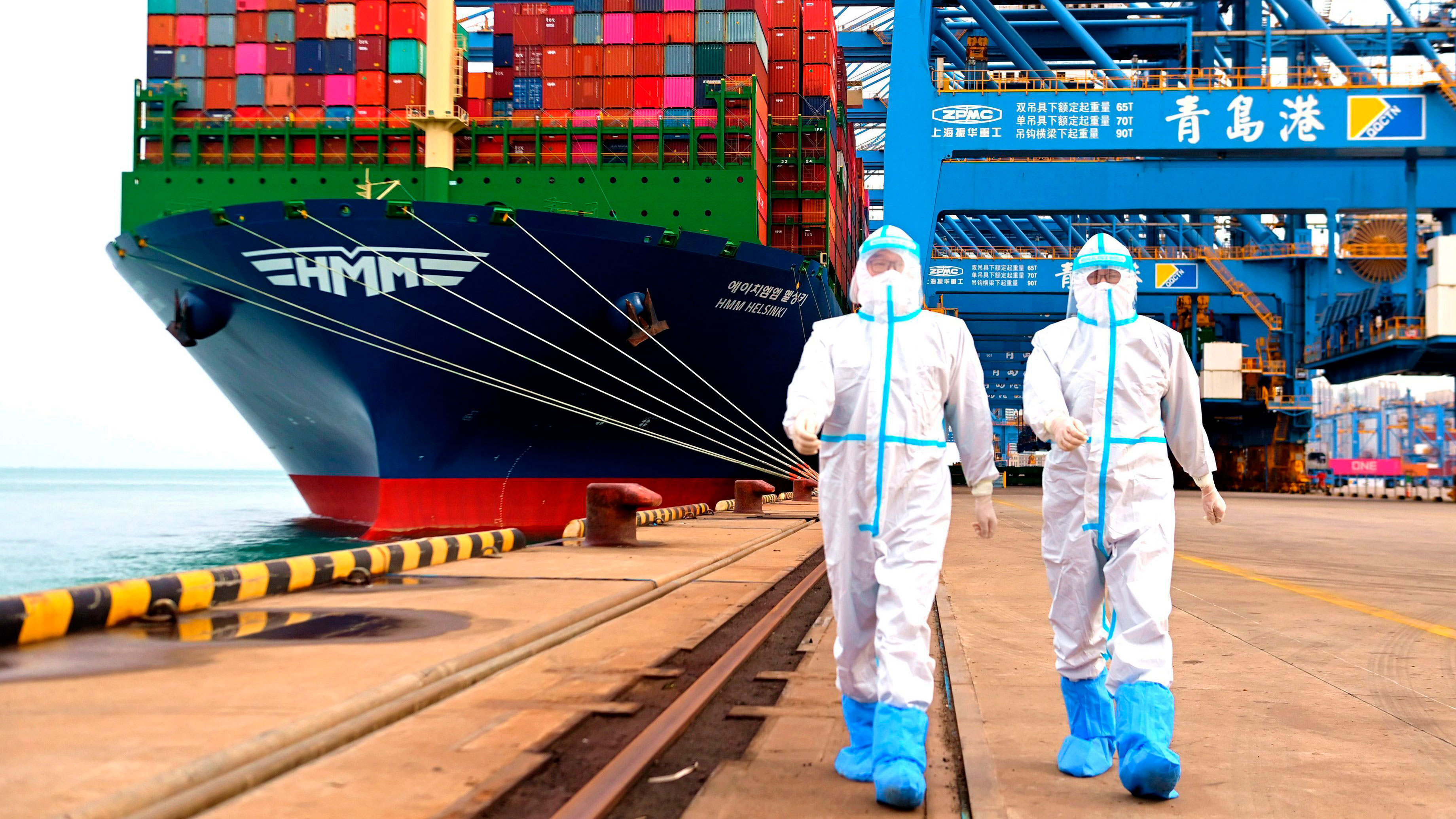 China immigration inspection officers in protective overalls march near a container ship at a port in Qingdao in eastern China's Shandong province.